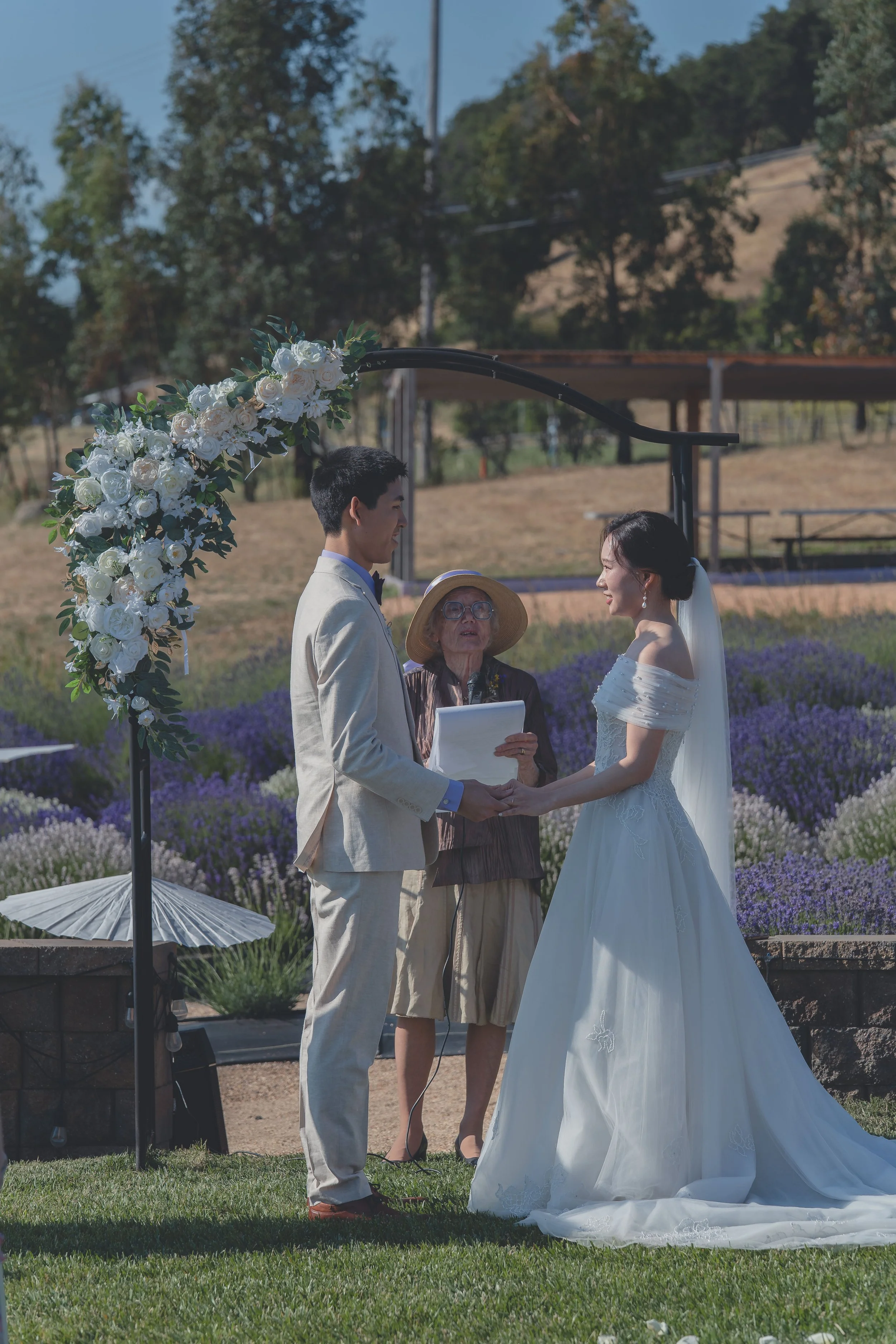 Bride and groom standing hand in hand during the ceremony in California wine country.