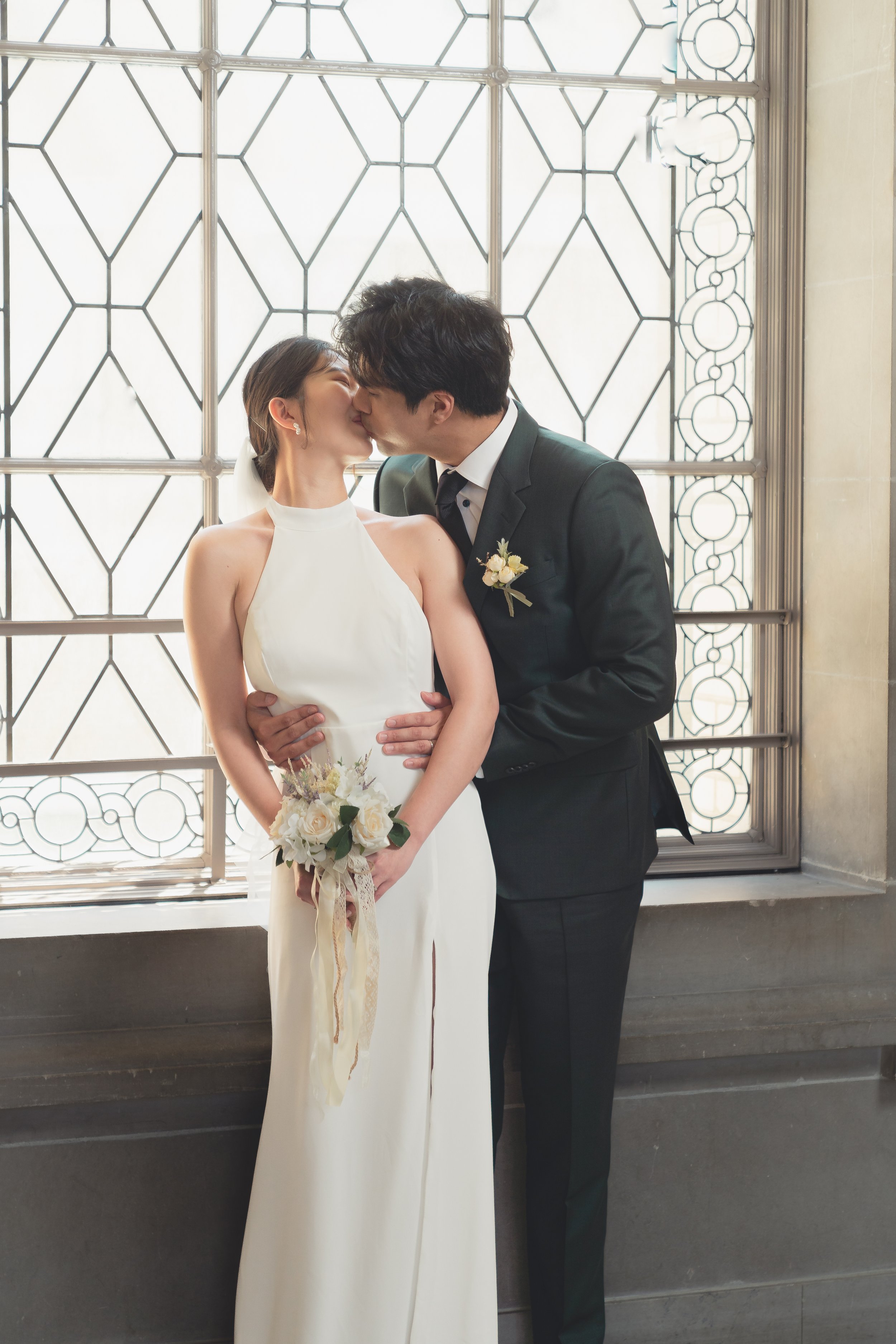 Intimate wedding portrait of a couple standing by the window inside San Francisco City Hall.