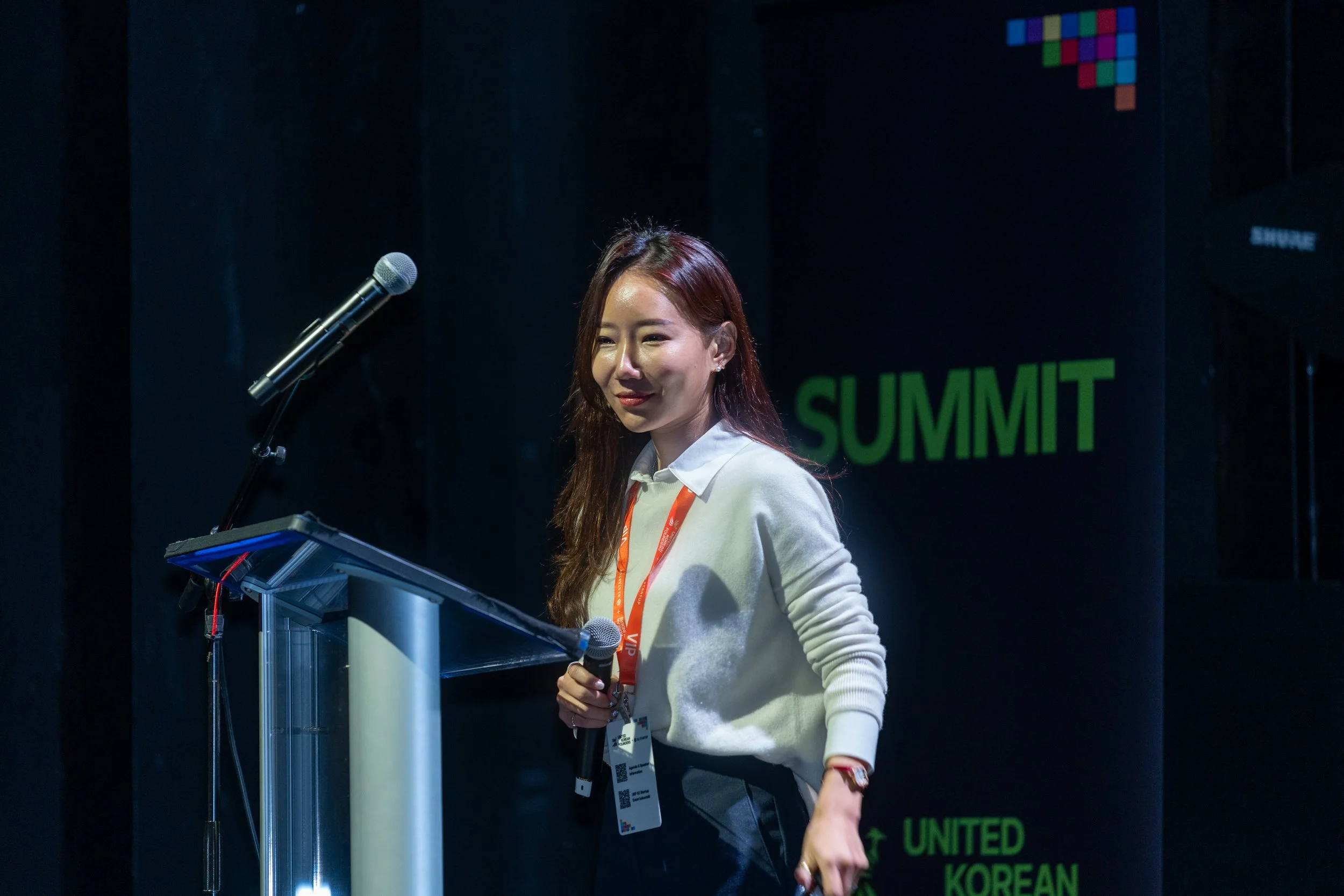 Woman speaking at a podium with a microphone during a summit event.