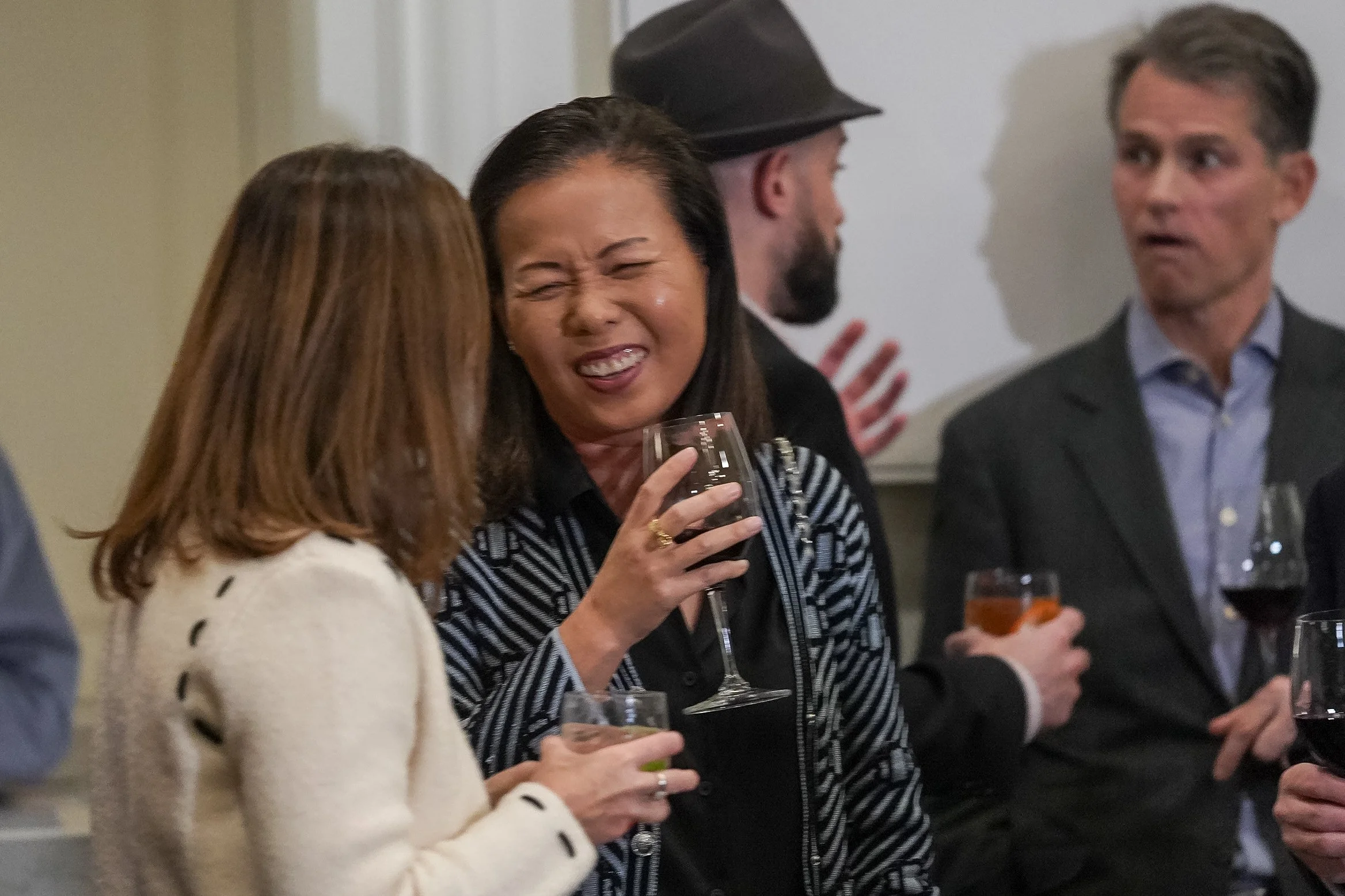 People at a social event, smiling and holding drinks.