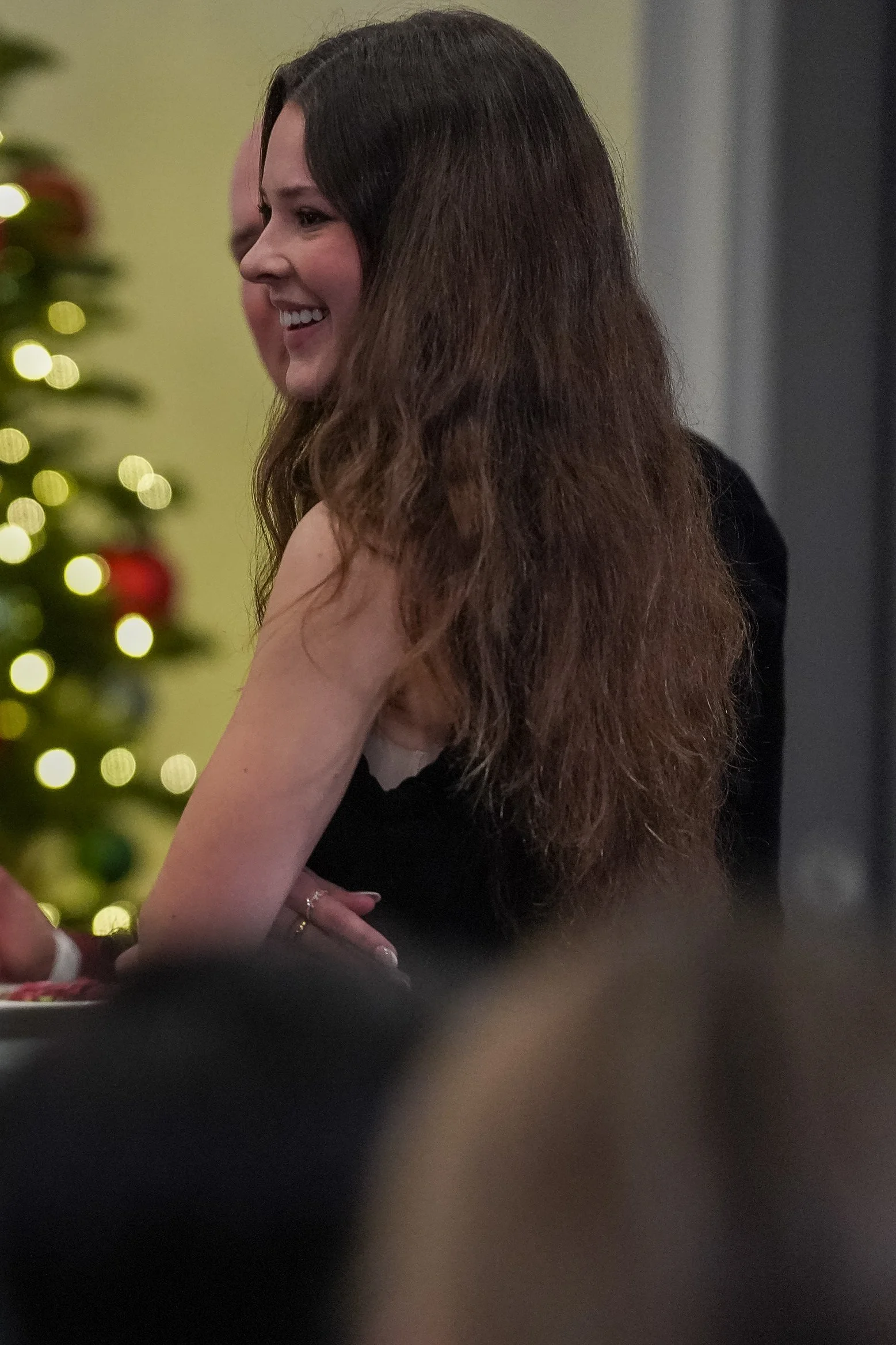 Woman smiling at an event with Christmas tree in the background.