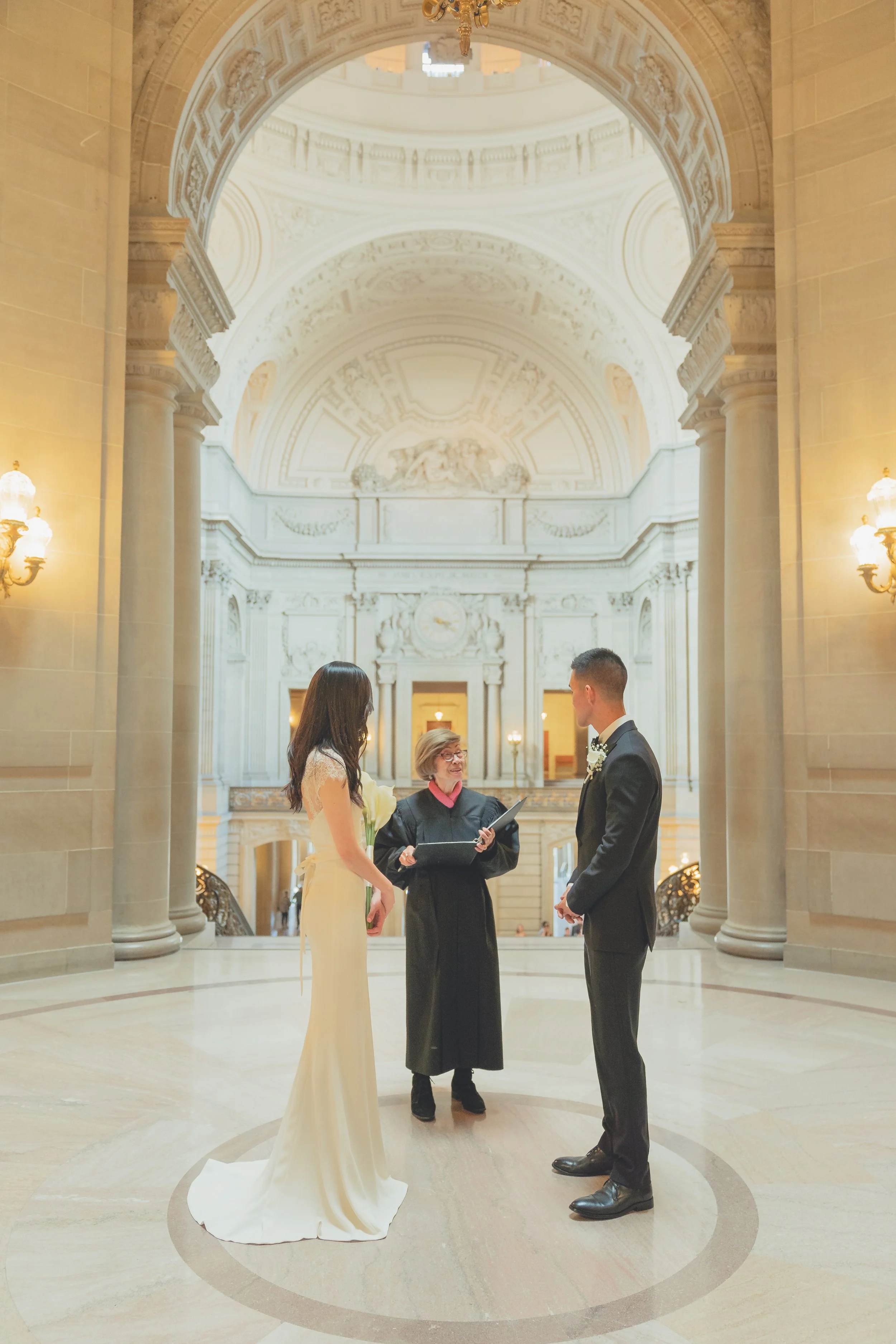 Wedding couple embracing in front of San Francisco City Hall with the iconic dome in the background.