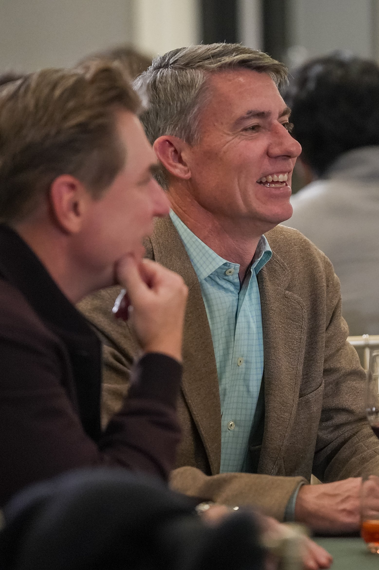 Two people seated at a table, engaged in conversation and smiling.