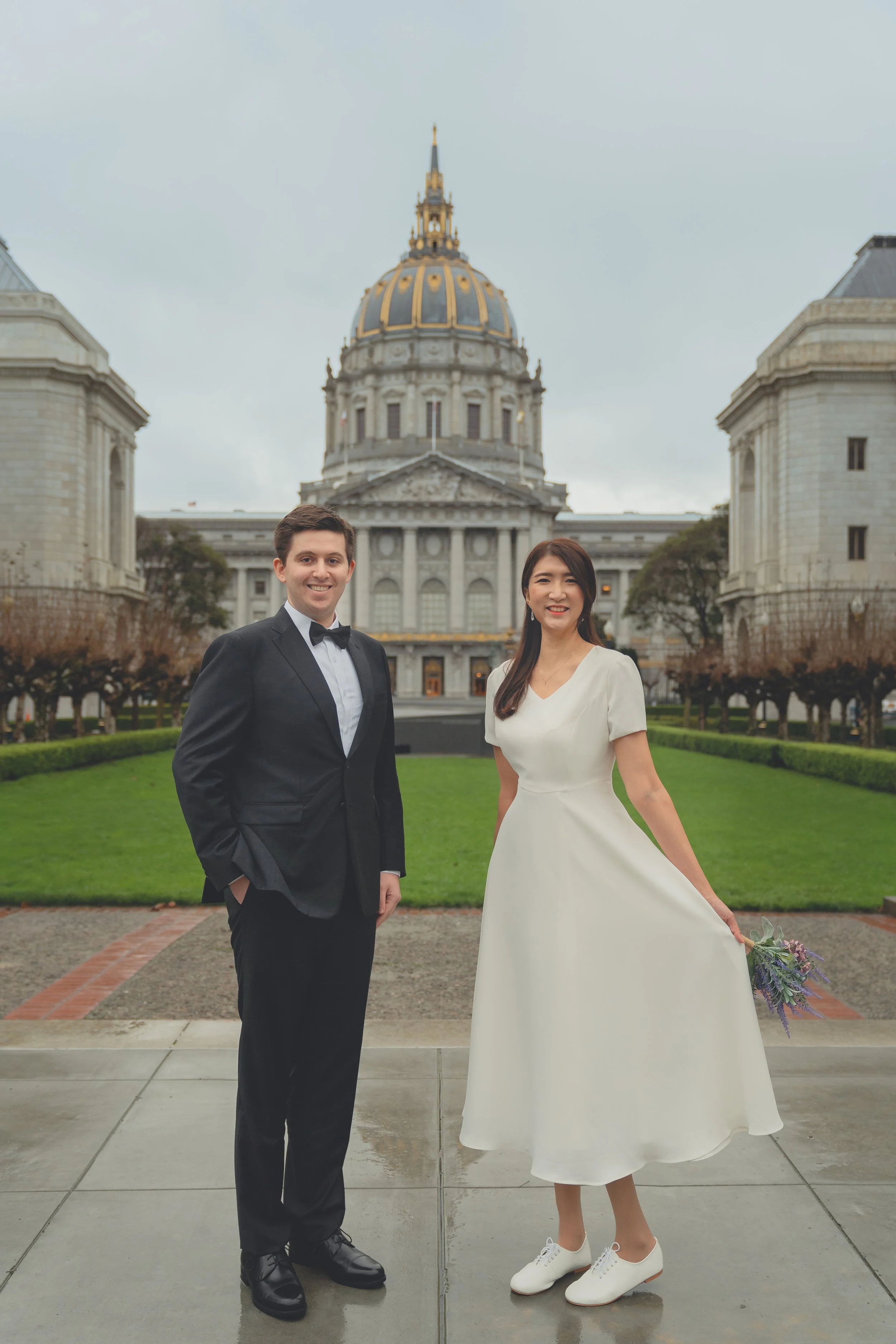 Bride and groom posing in front of San Francisco City Hall with the iconic dome in the background.