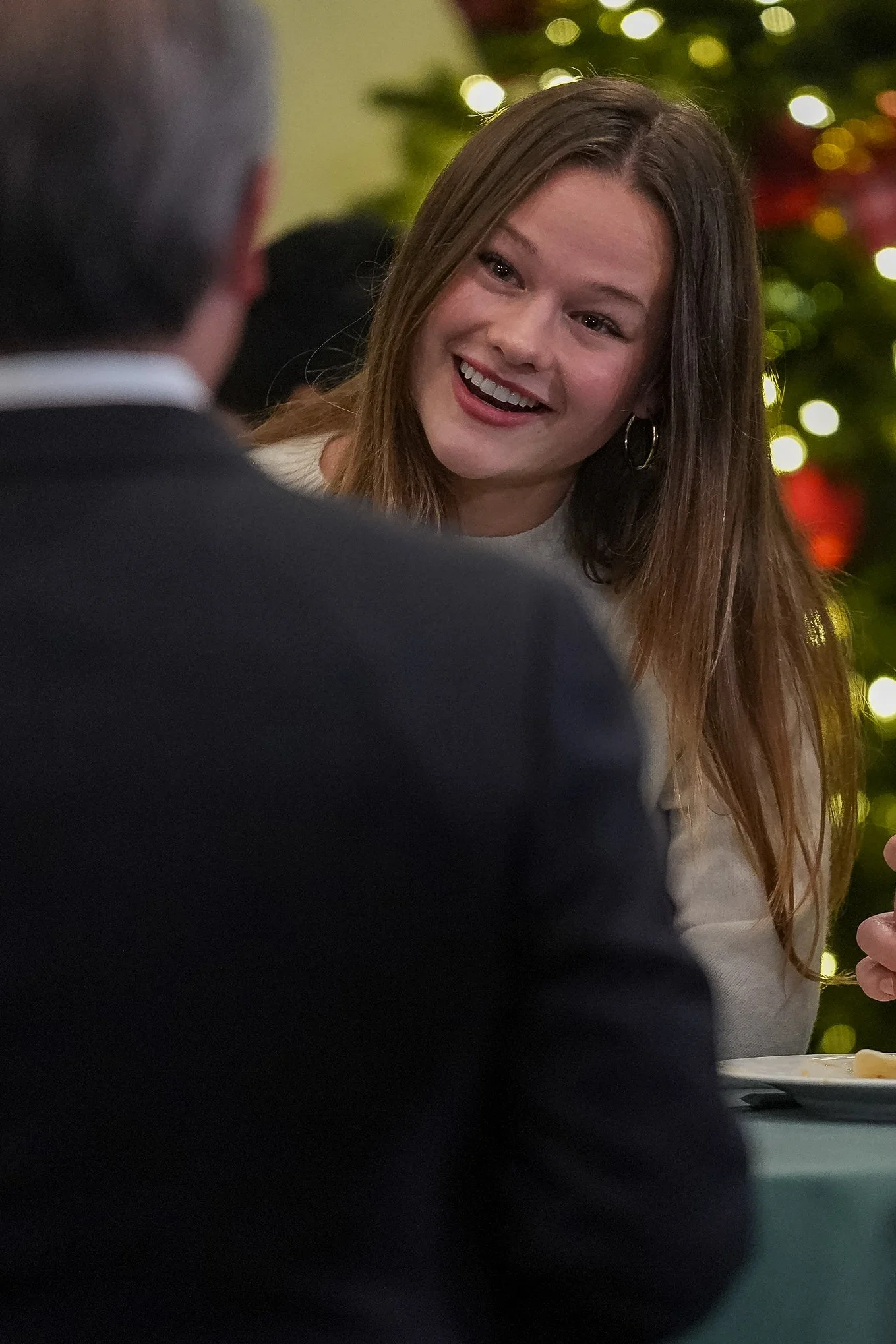 Woman smiling in conversation near a Christmas tree