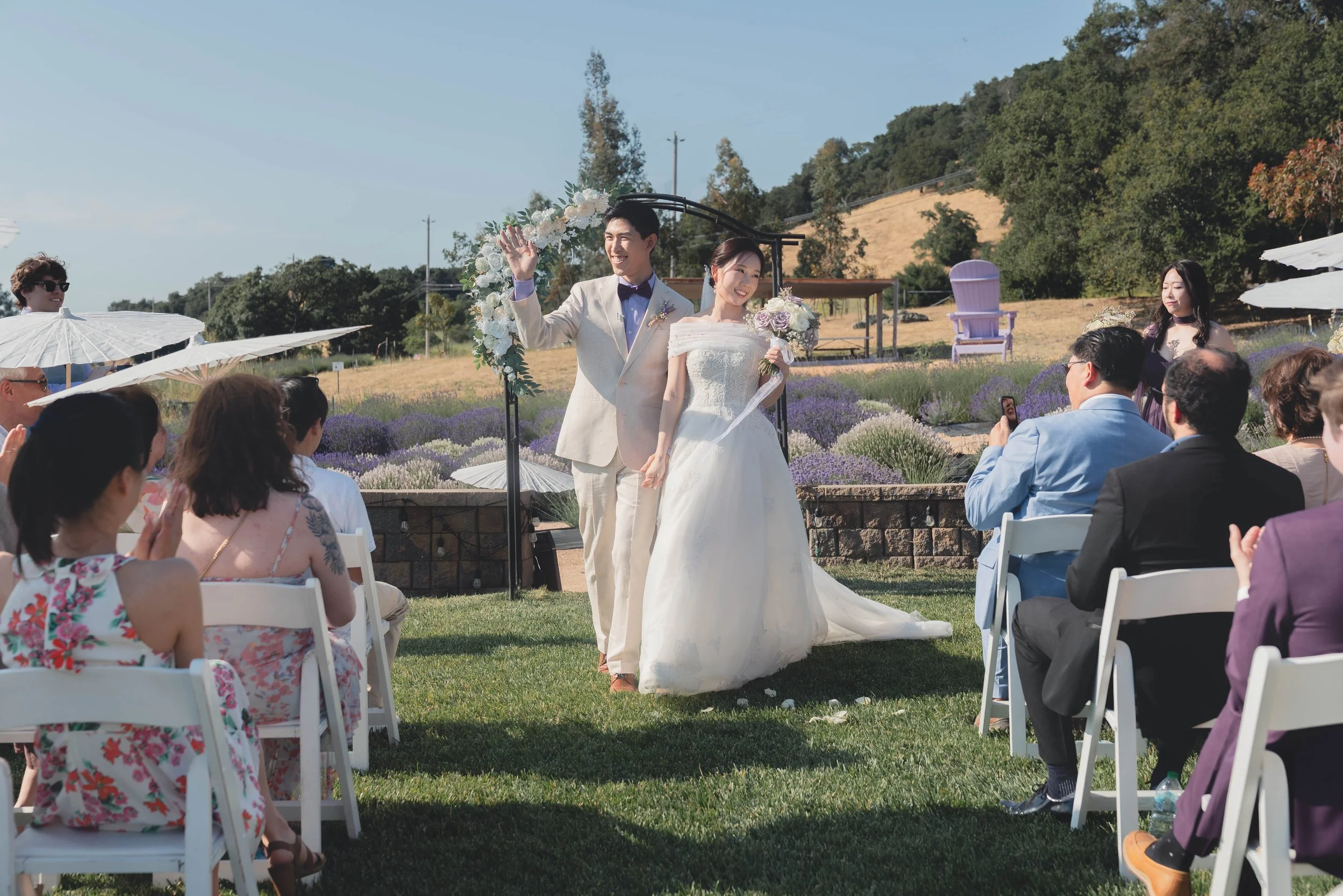Bride and groom standing together as guests rise during the ceremony in Sonoma.