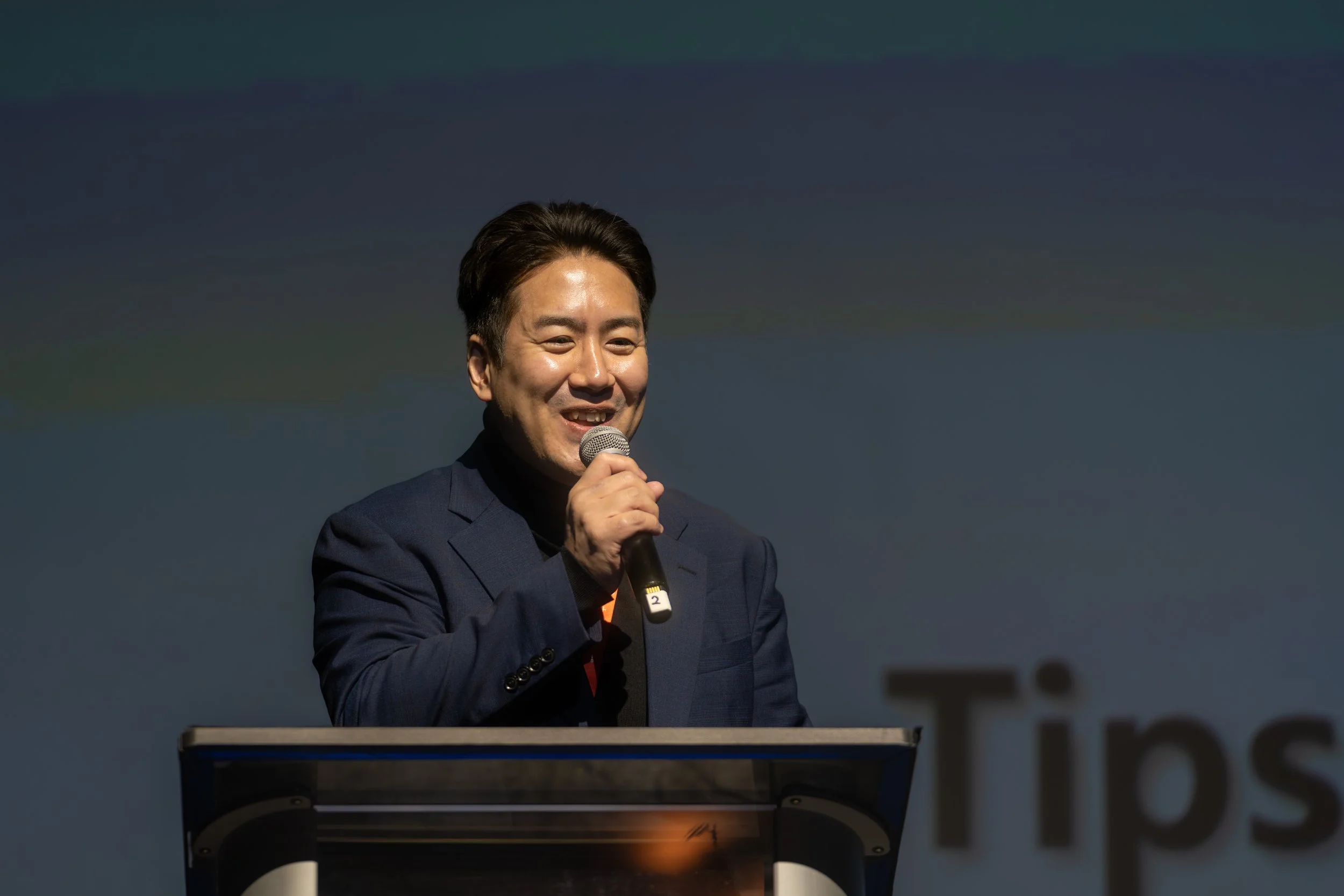 Man wearing a suit speaking into a microphone at a podium.