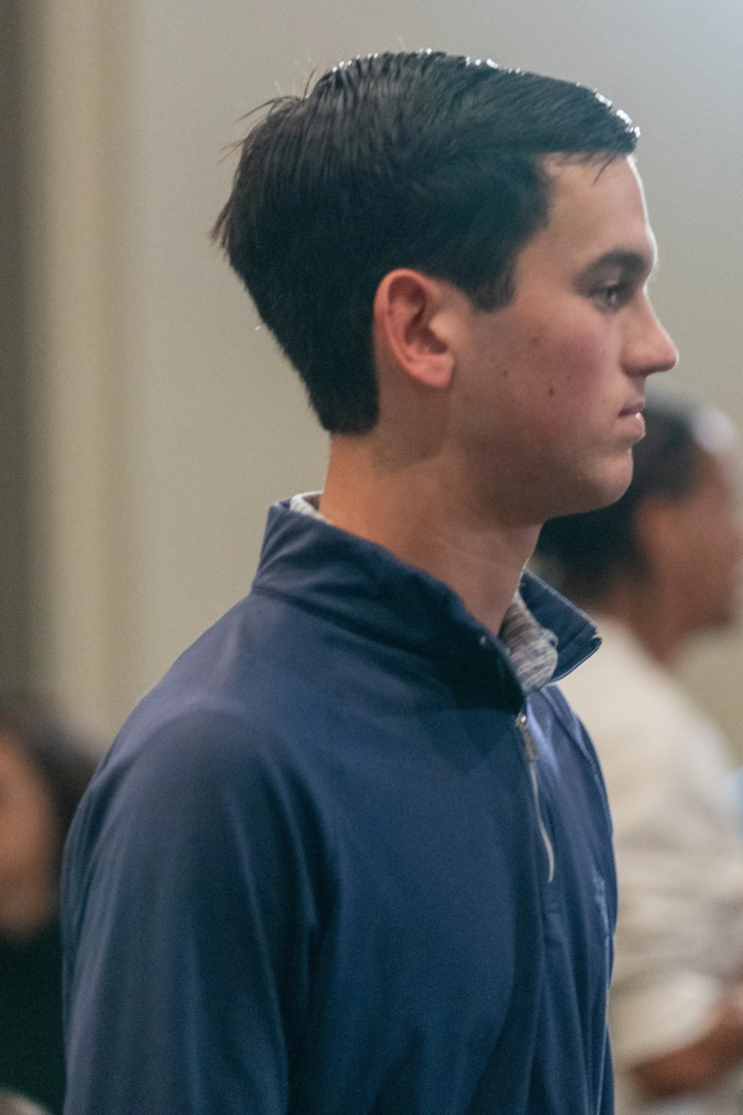 Profile view of a person in a blue jacket with short dark hair.