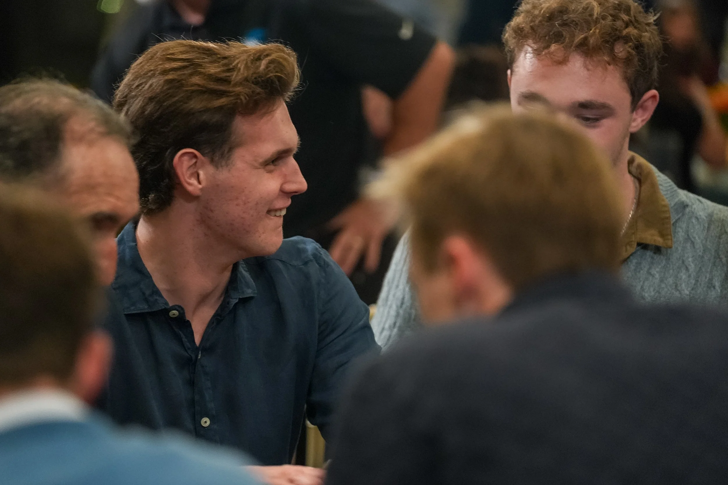 Group of people at a poker table, engaged in conversation during a card game.
