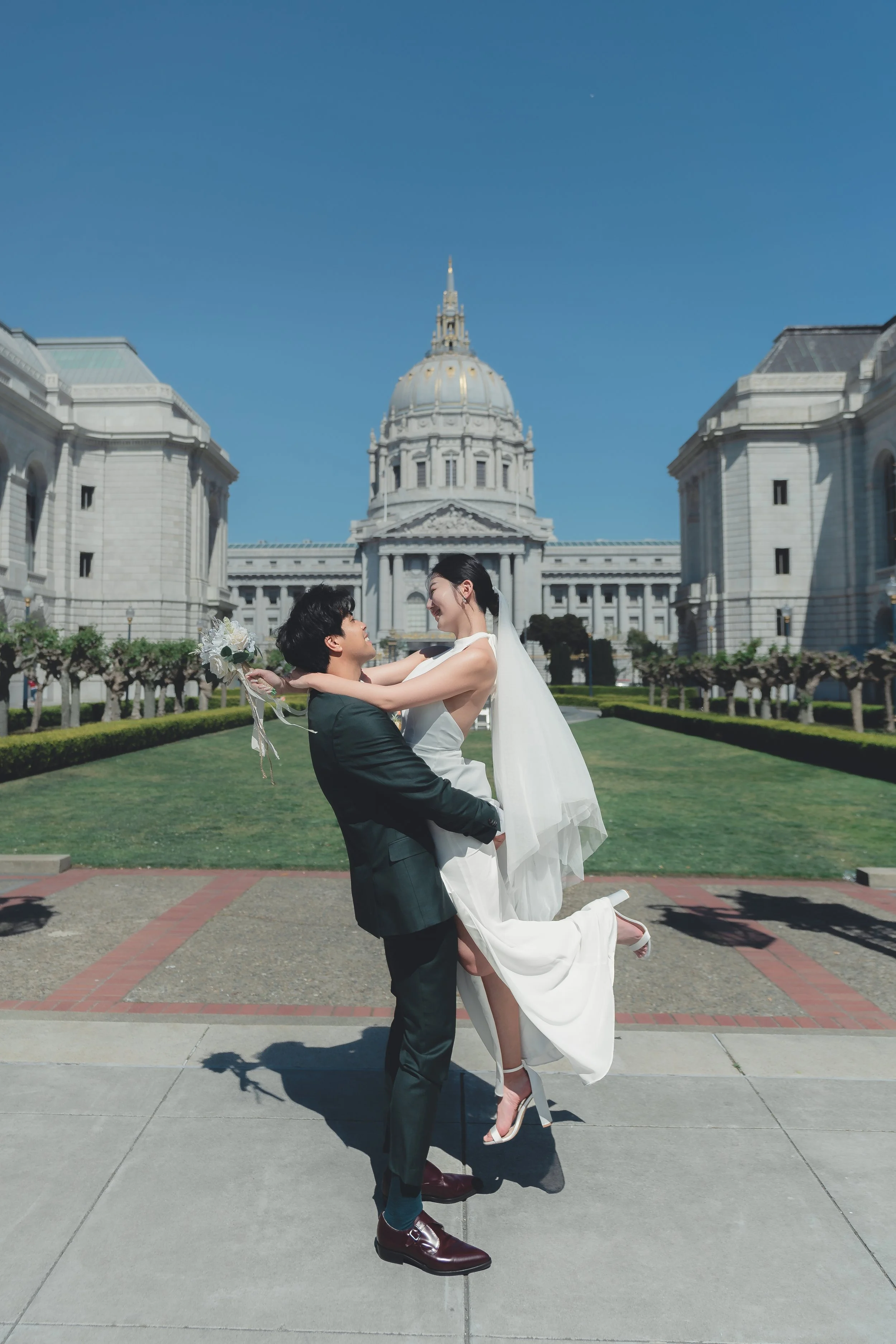 Wedding couple embracing in front of San Francisco City Hall with the iconic dome in the background.