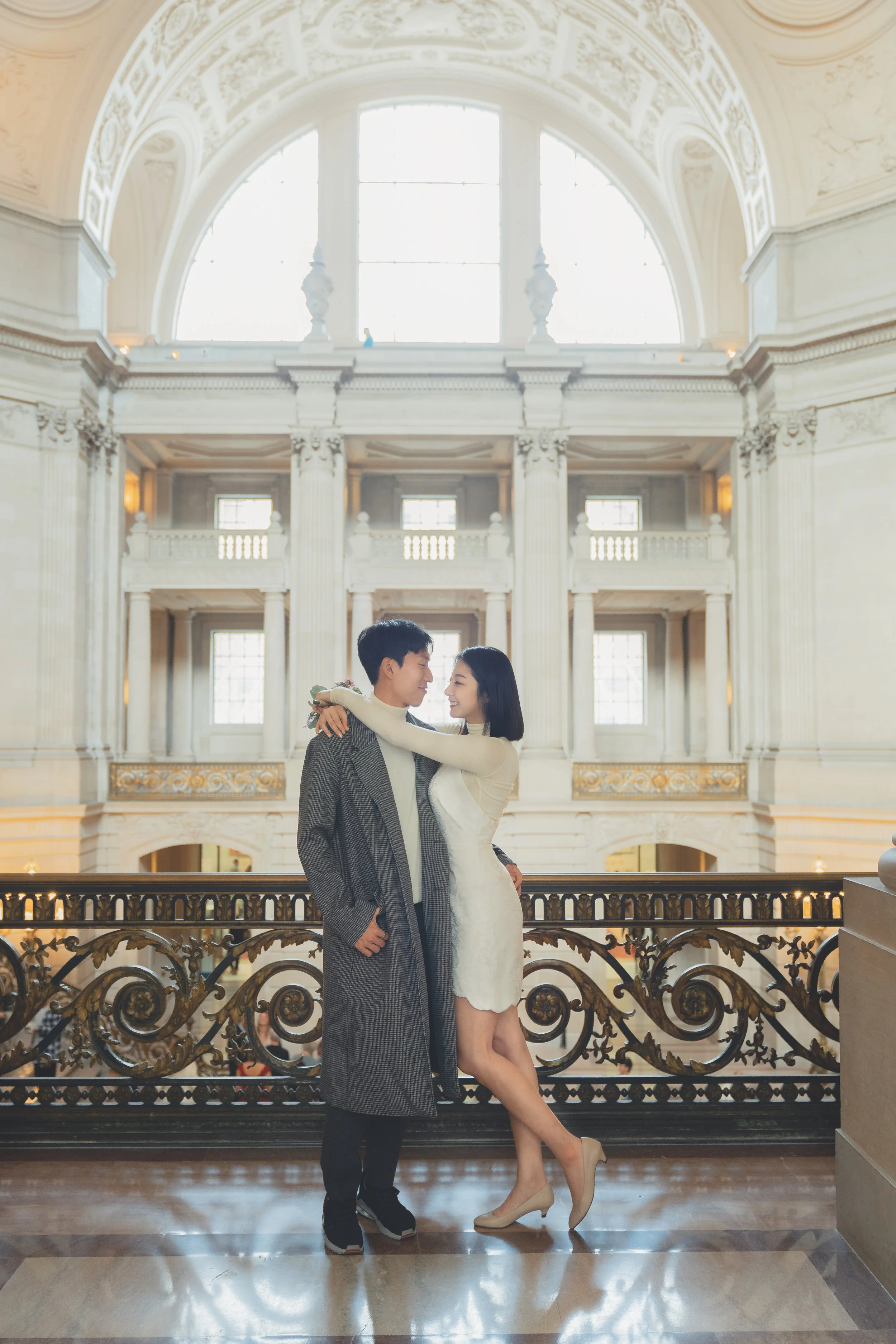 Wedding couple embracing at the rotunda balcony inside San Francisco City Hall.
