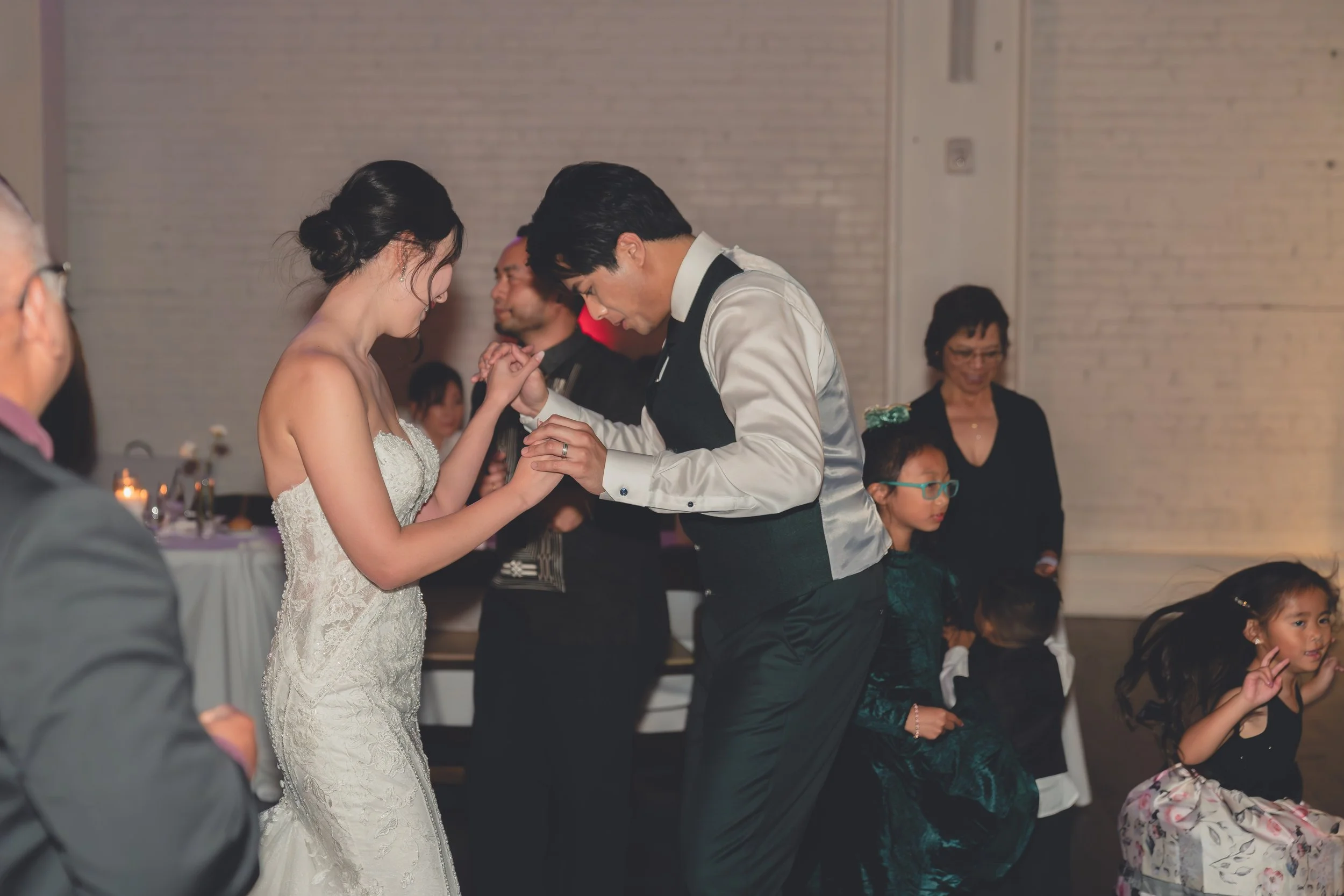 A bride and groom dancing at a wedding reception with guests watching in the background.