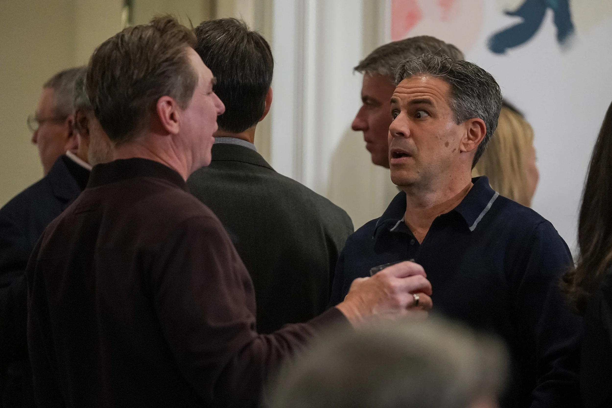 Group of people engaged in conversation at a social event indoors.