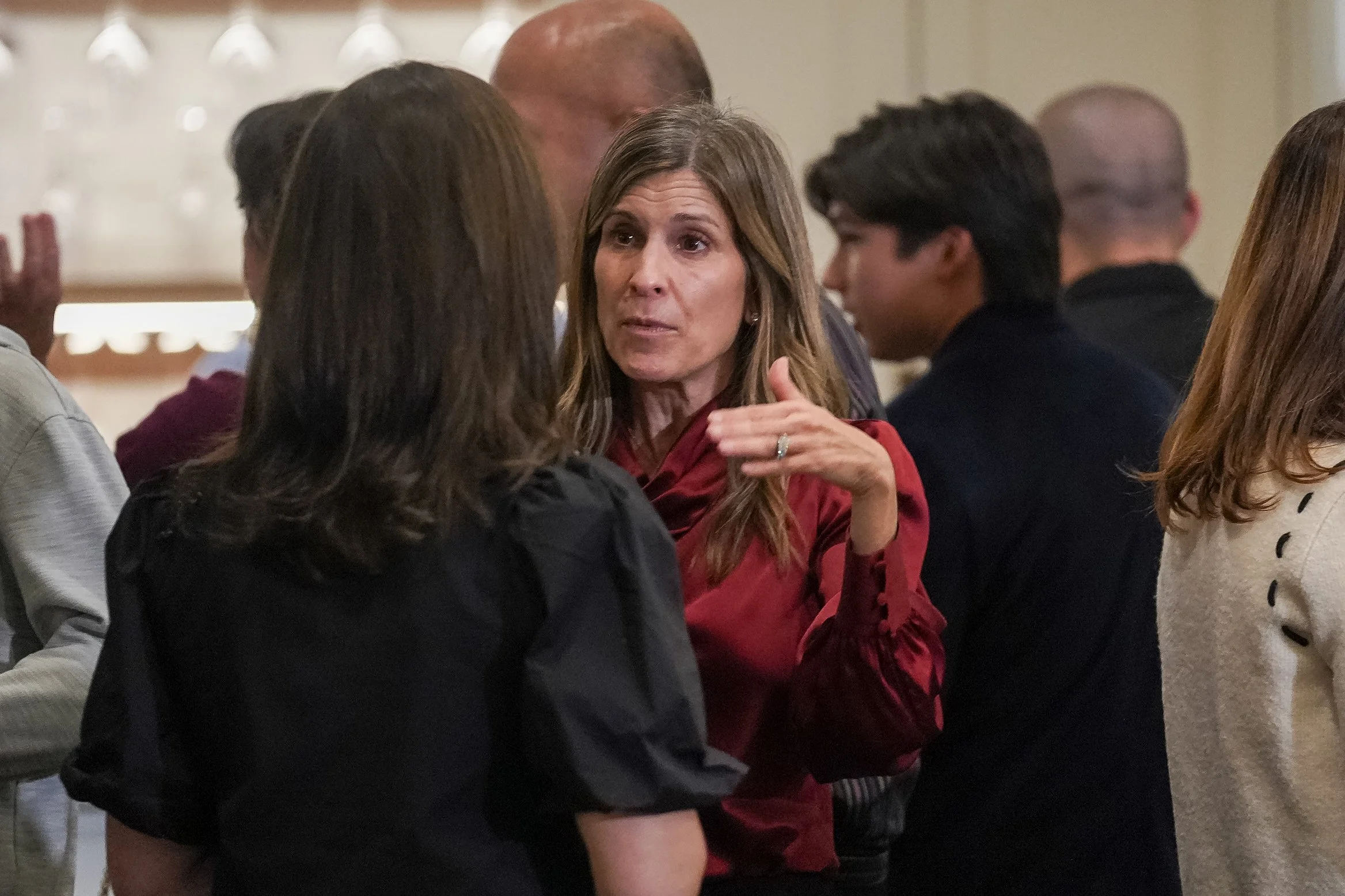 Group of people in conversation at an indoor event, focusing on two women engaged in discussion.