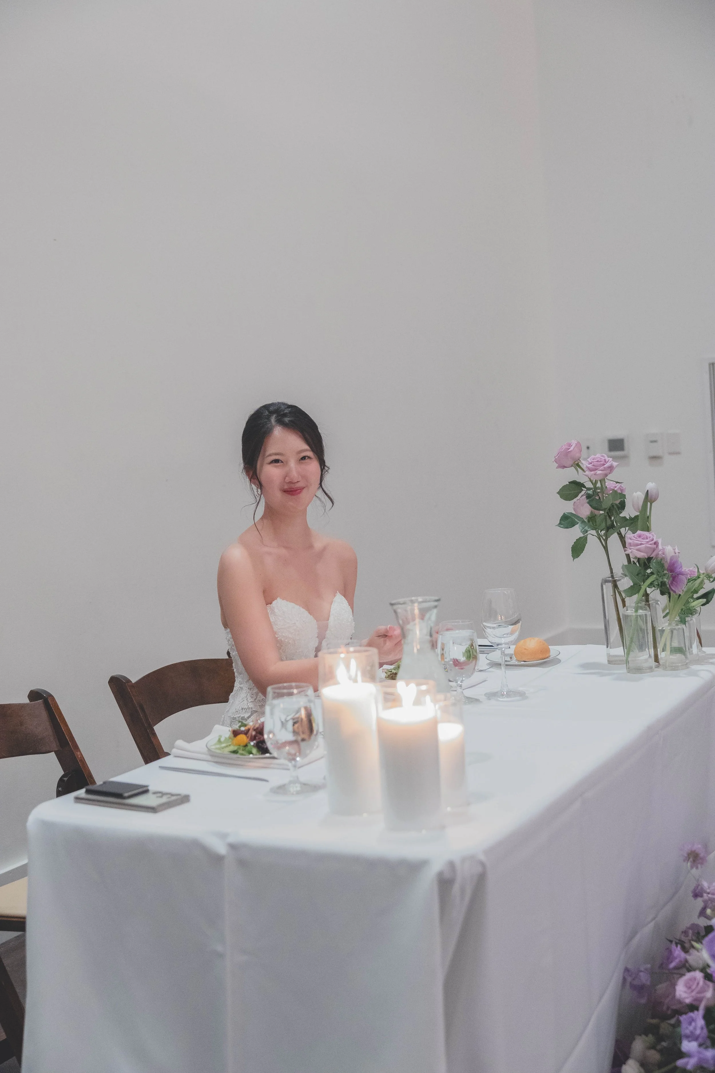 Bride sitting at a decorated table with candles and flowers.
