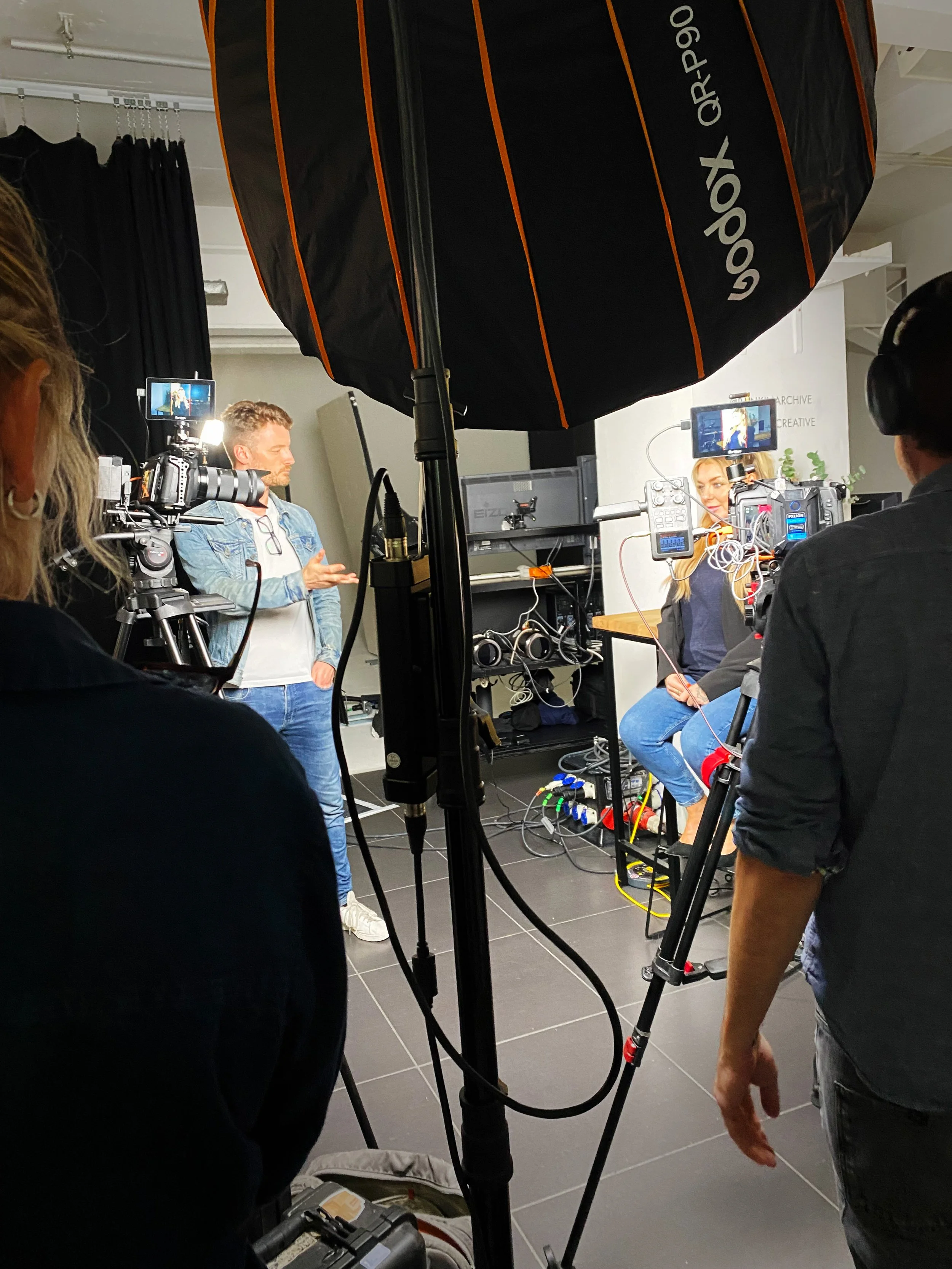 Ali directing a shoot. Filming equipment sits in the foreground.