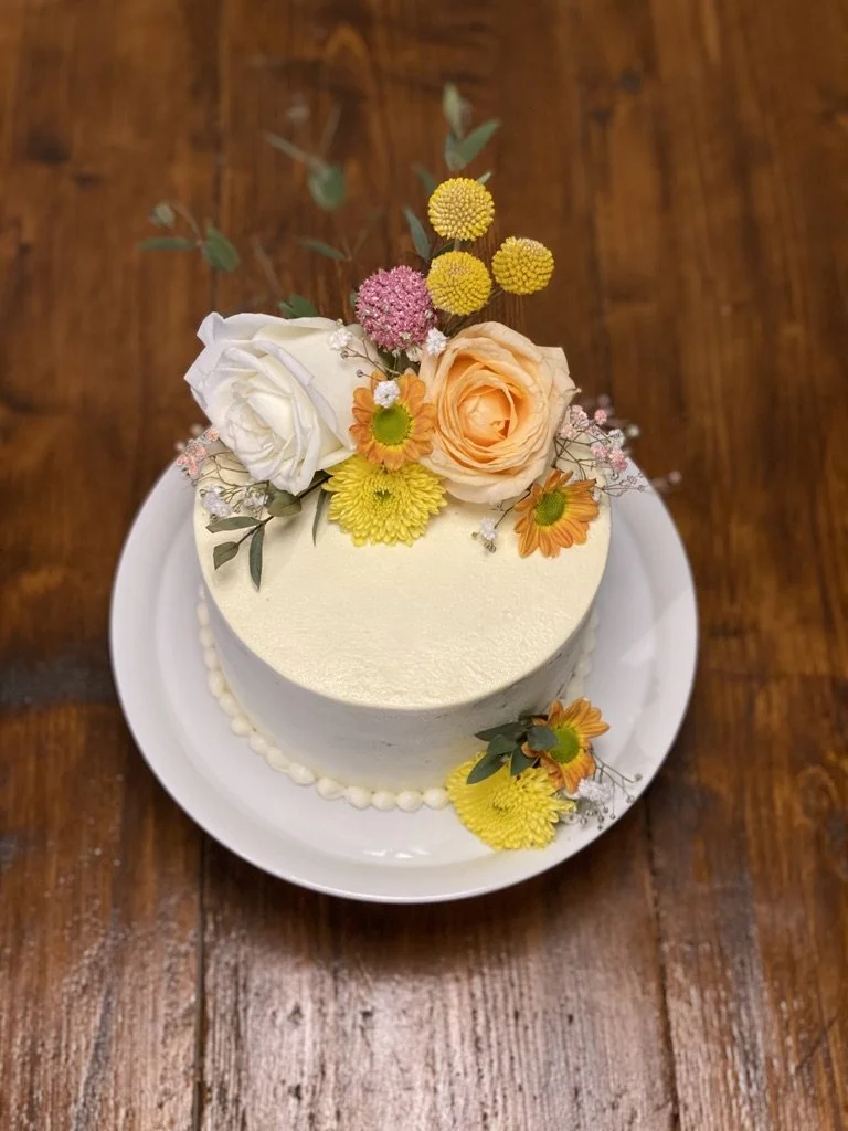 Weiße Torte mit Rosen und gelben Blüten