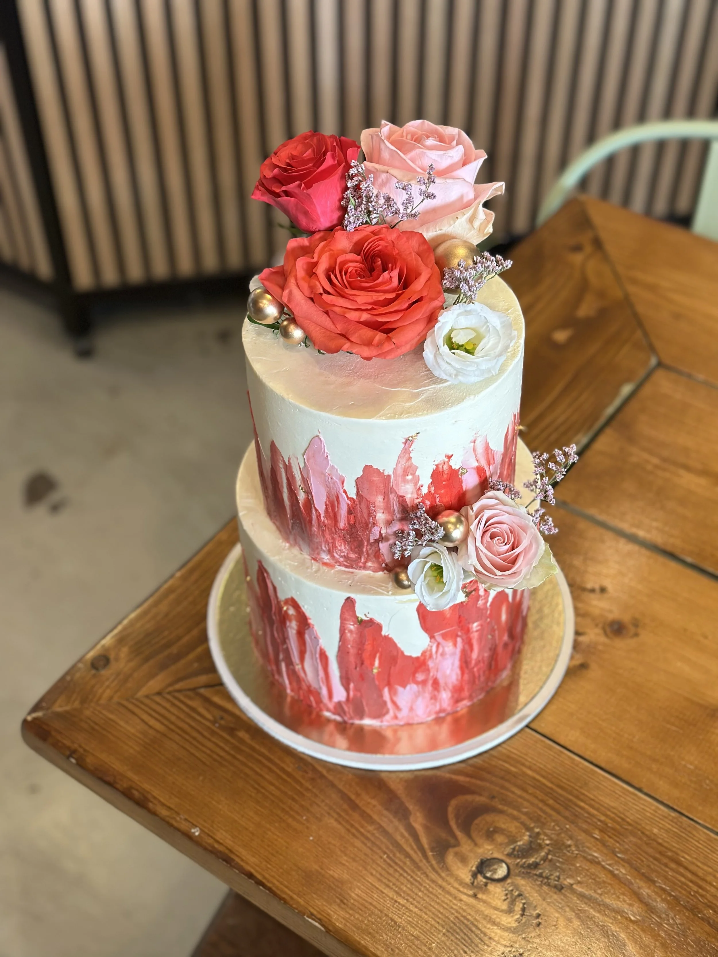 Zweistöckige Torte in Weiß und Rot mit roten Rosen