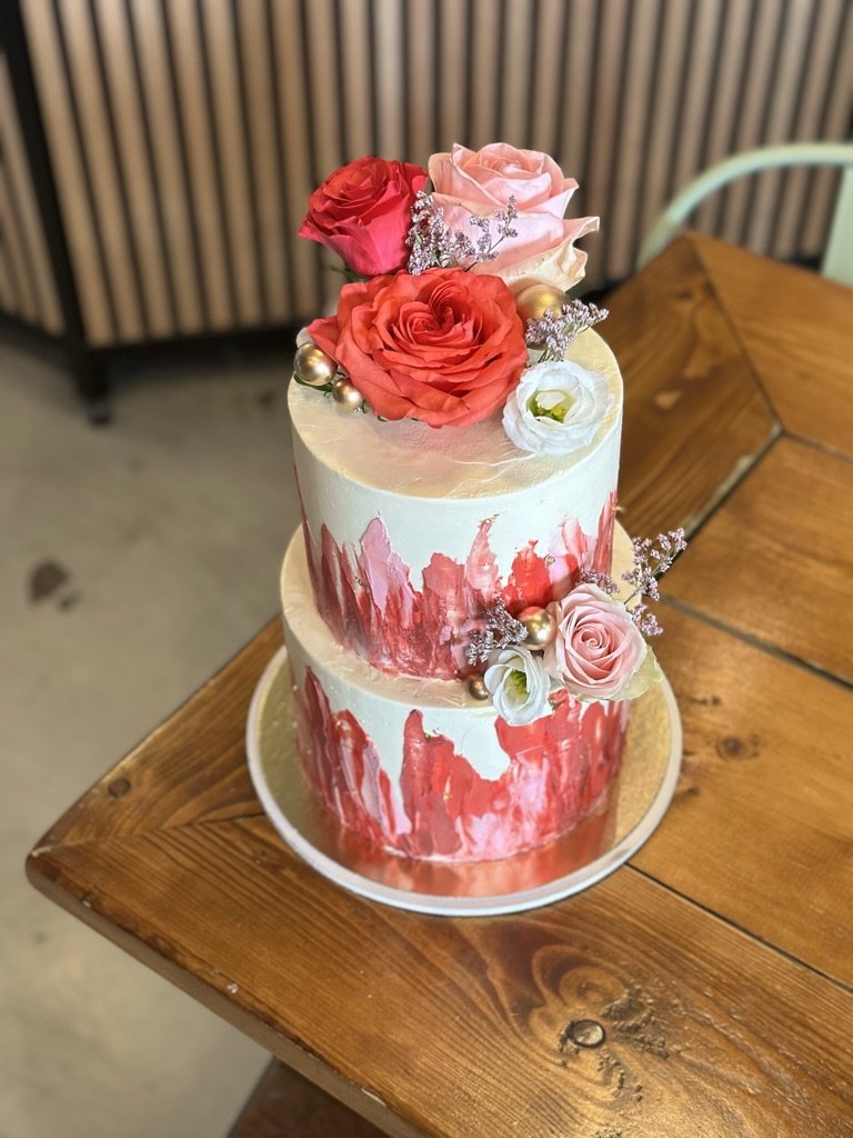 Zweistöckige Torte in Weiß und Rot mit roten Rosen