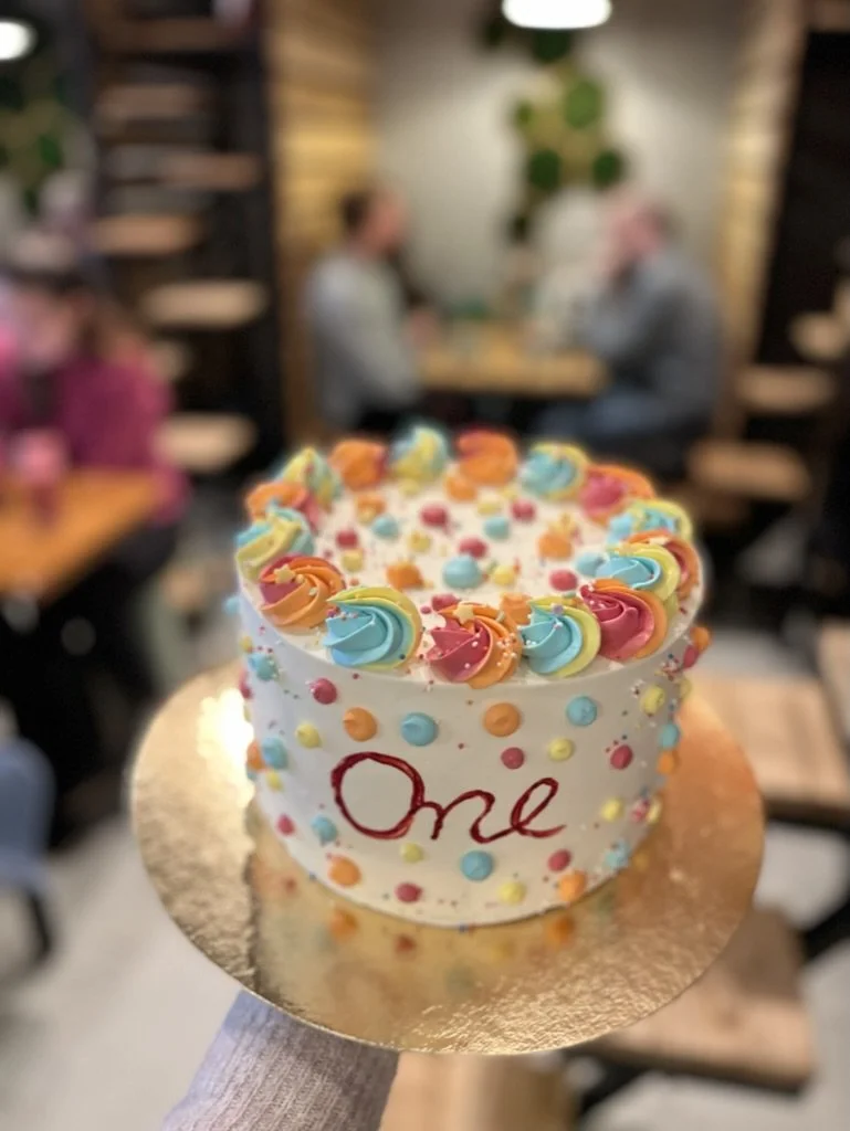 Torte mit bunten Sahnetupfen und Schriftzug One