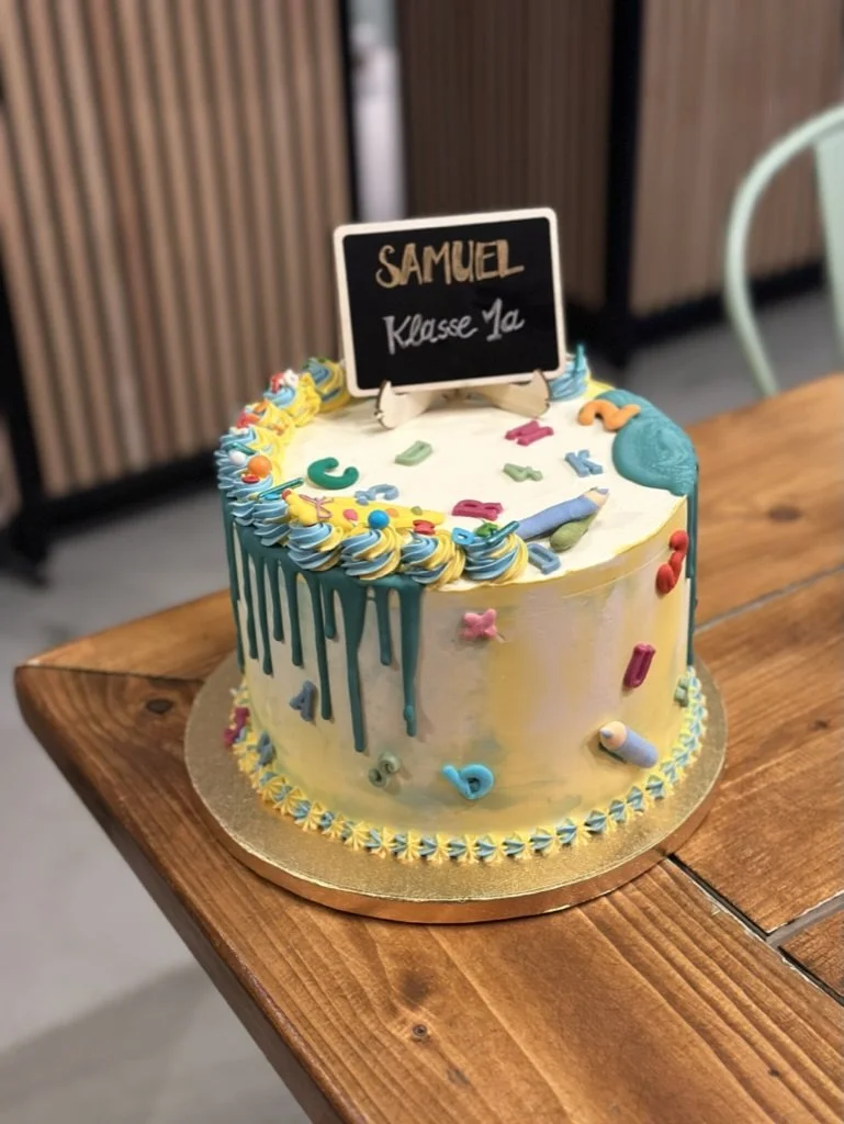 Torte zur Einschulung mit türkisem Drip und Tafel-Topper auf einem Holztisch