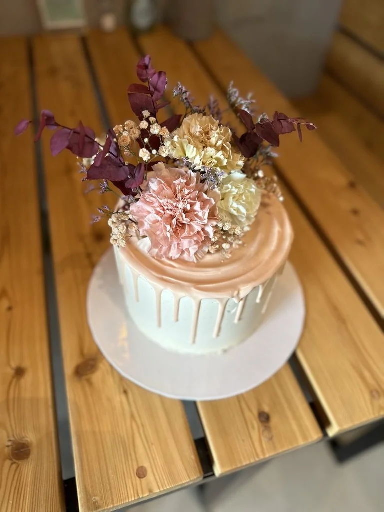 Torte mit Drip und Trockenblumen auf einem Holztisch