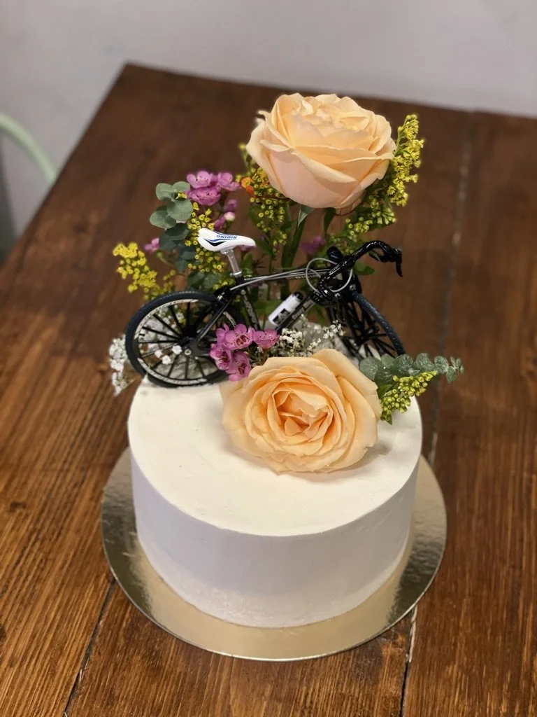 Weiße Torte mit Fahrrad-Topper und Rosen
