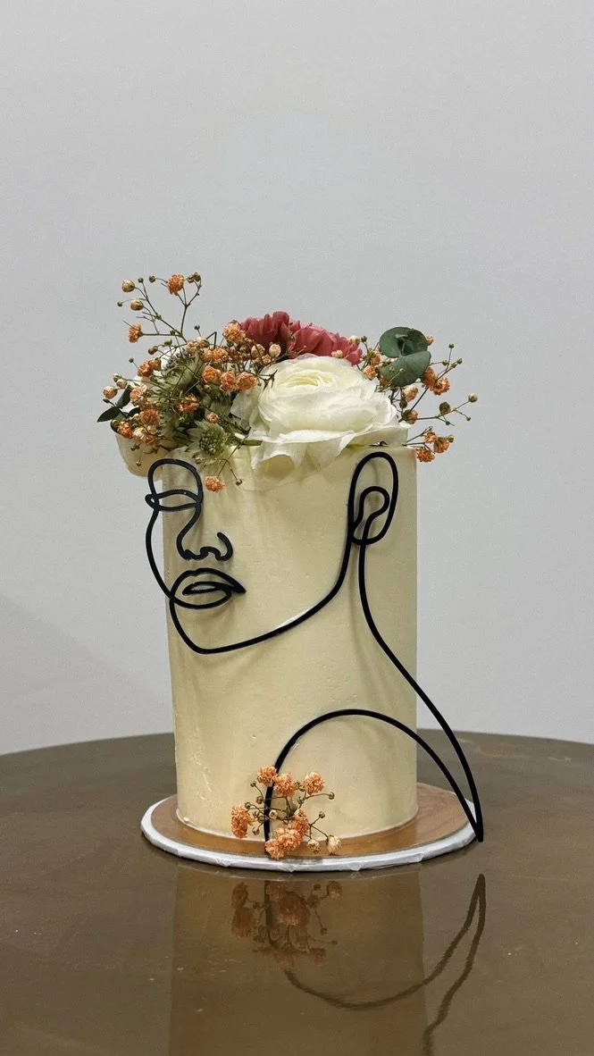 Mini-Torte mit Line-Art-Gesicht und Blumenkranz