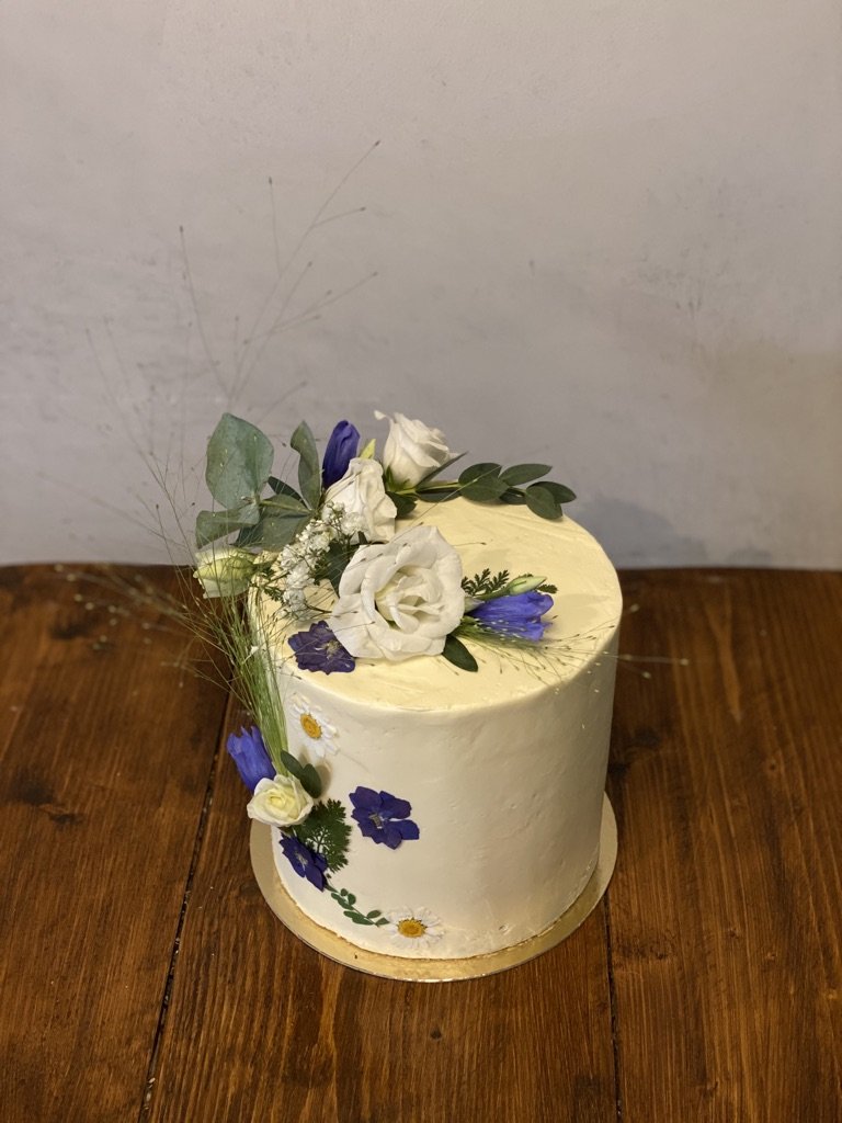 Weiße Torte mit violetten und weißen Blüten