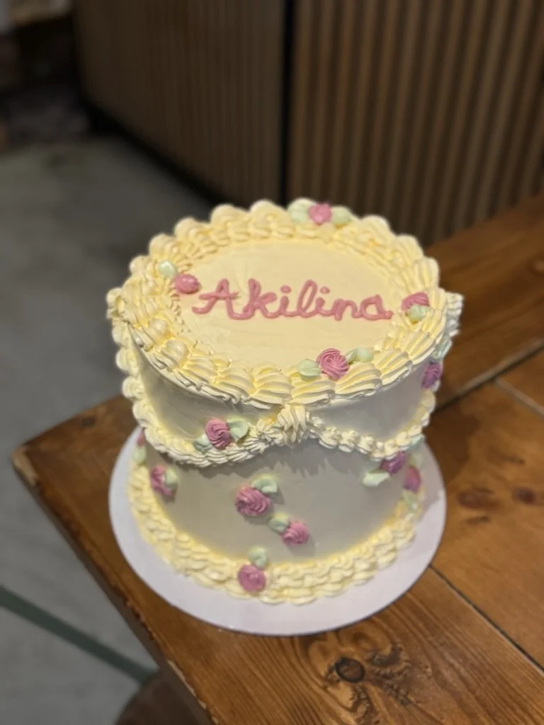 Gelbe Vintage-Piping-Torte mit rosa Schriftzug und kleinen Rosen