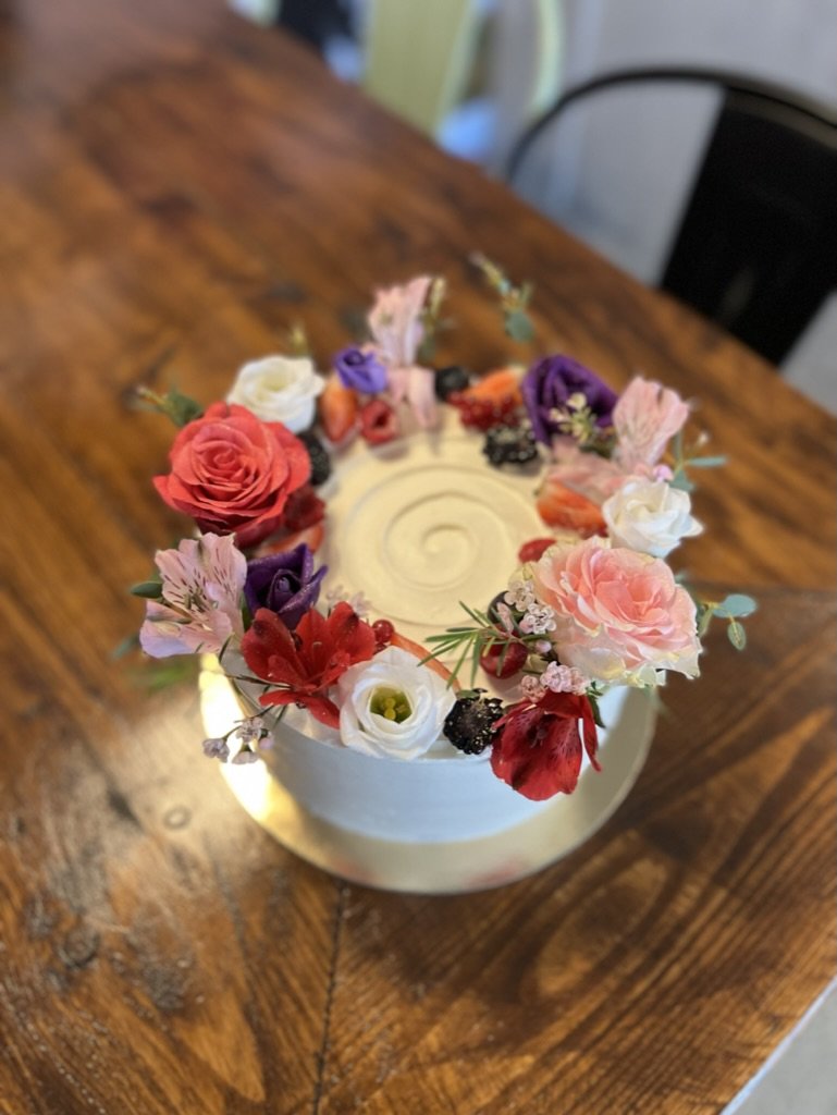 Weiße Torte mit buntem Blumenkranz