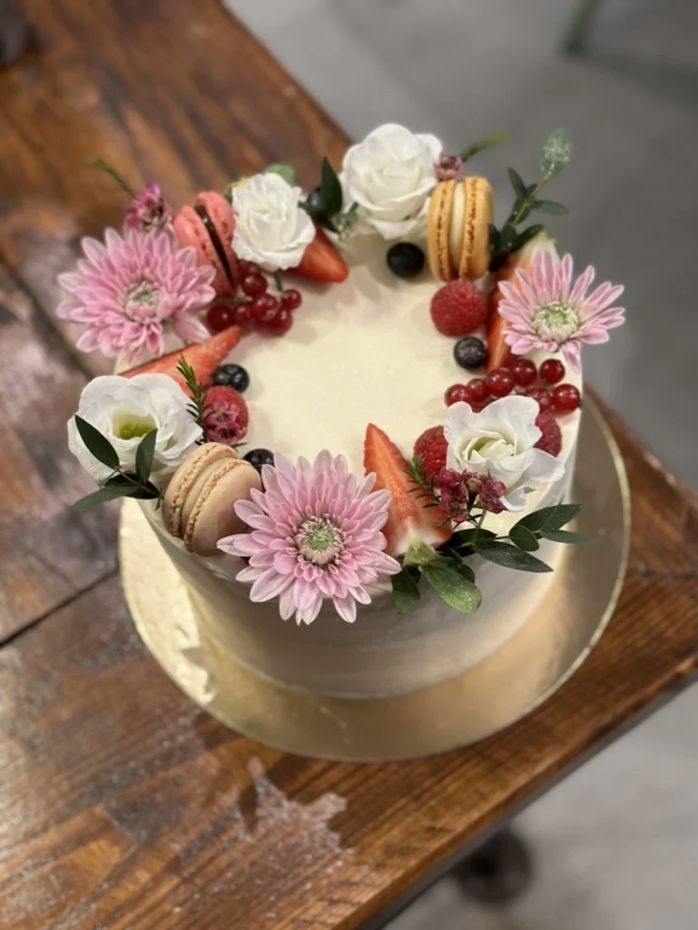 Weiße Torte mit Blumenkranz aus Gerbera, Rosen und Macarons