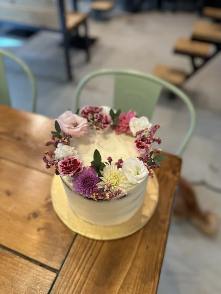 Kleine Torte mit Blumenkranz in Rosa und Violett