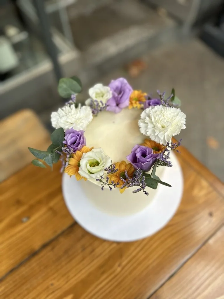 Weiße Torte mit Blumenkranz in Weiß und Violett