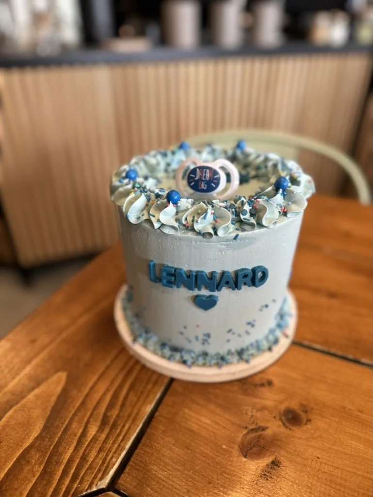 Hellblaue Torte mit Namens-Schriftzug und Schnuller-Deko