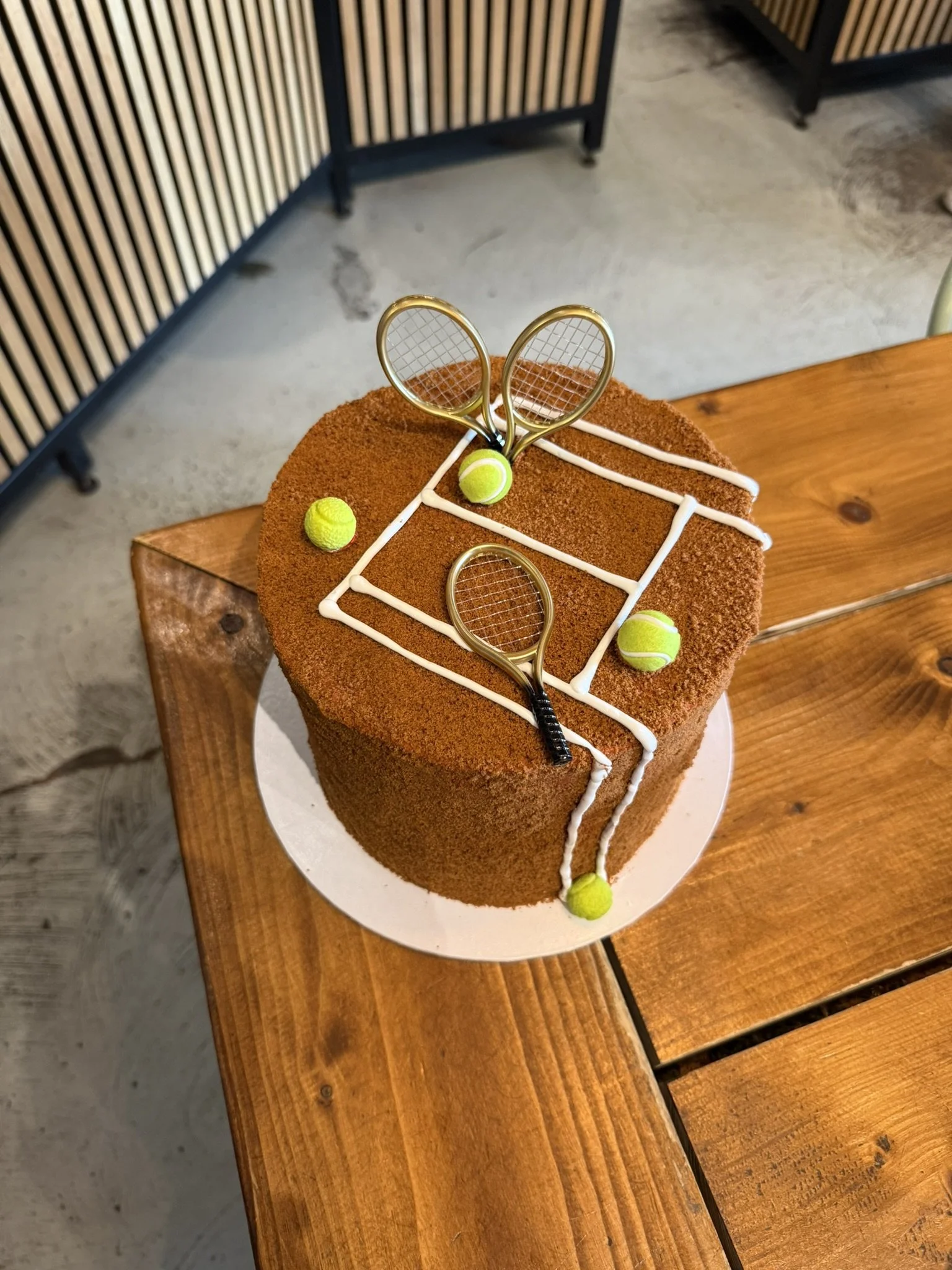 Tennis-Torte als Sandplatz auf einem Holztisch