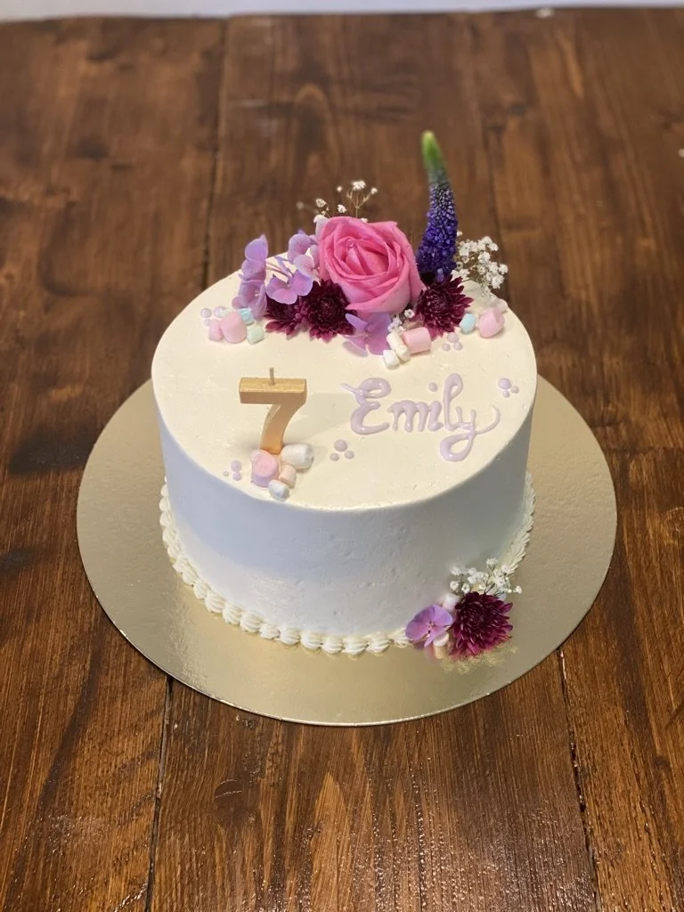 Weiße Torte mit pinken Blüten, Zahl 7 und Schriftzug