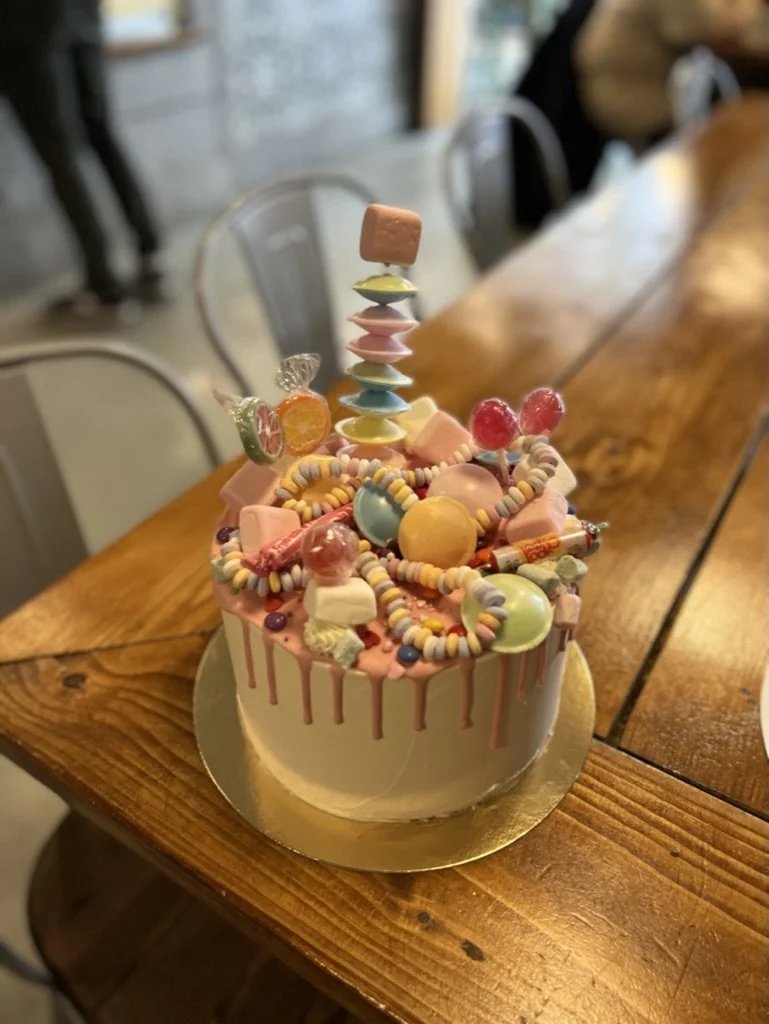 Drip-Torte mit bunten Süßigkeiten und Marshmallow-Spieß