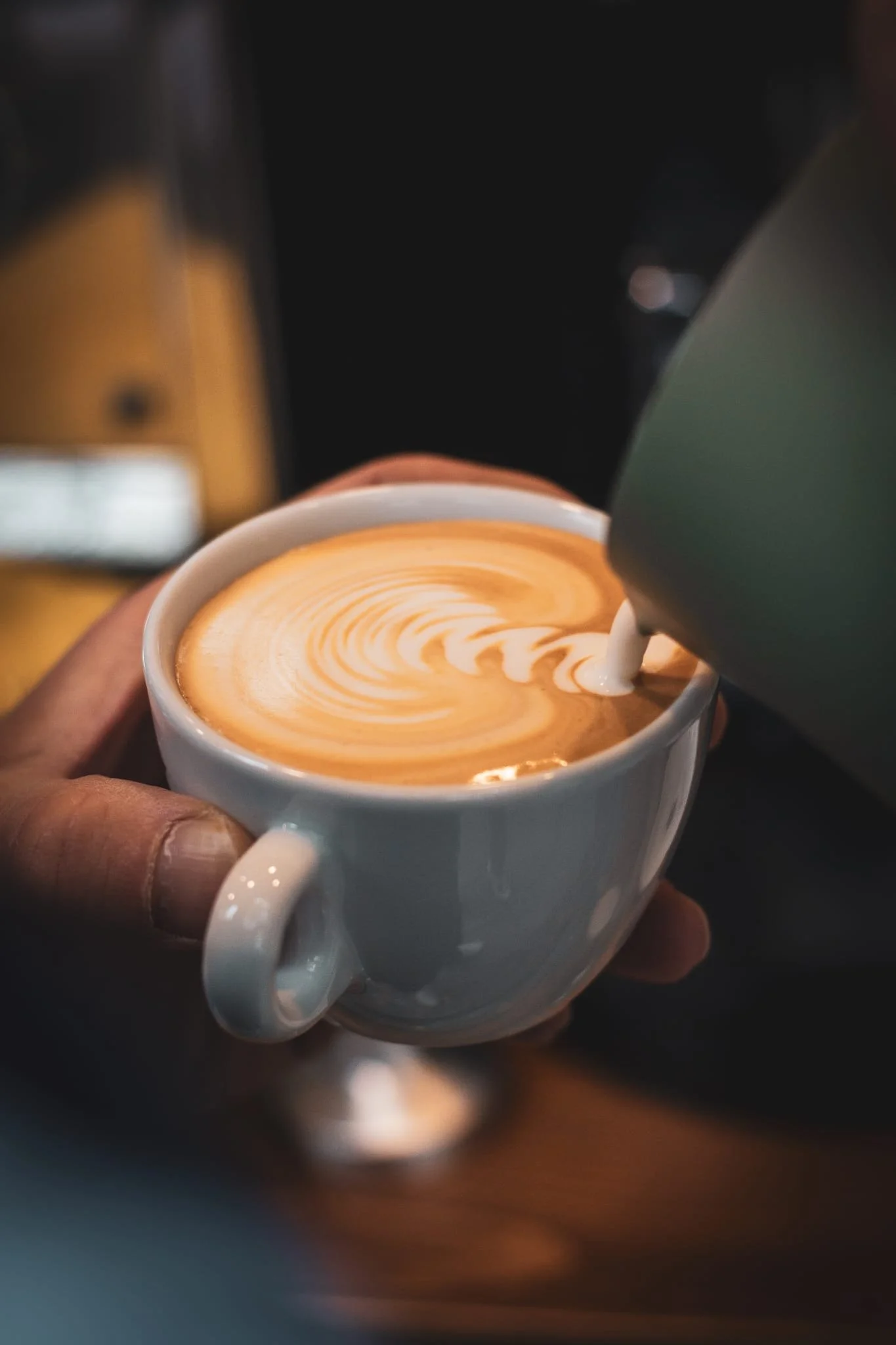Latte Art: Ein Barista gießt Milch in einen Cappuccino