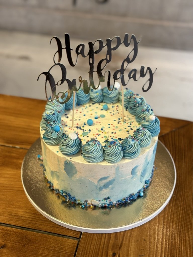 Blaue Torte mit Sahnetupfen und Happy-Birthday-Topper