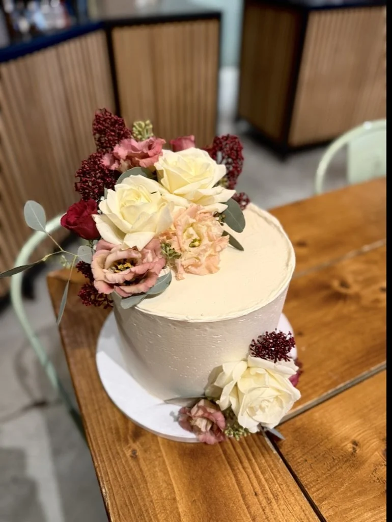 Weiße Torte mit Blumenbouquet in Creme, Rosa und Bordeaux im Café