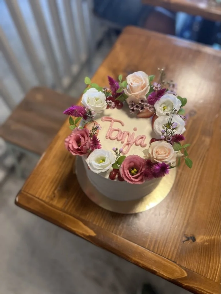 Weiße Torte mit Blumenkranz und Schriftzug