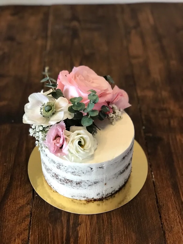 Semi-Naked-Torte mit rosa und weißen Blumen auf einem Holztisch