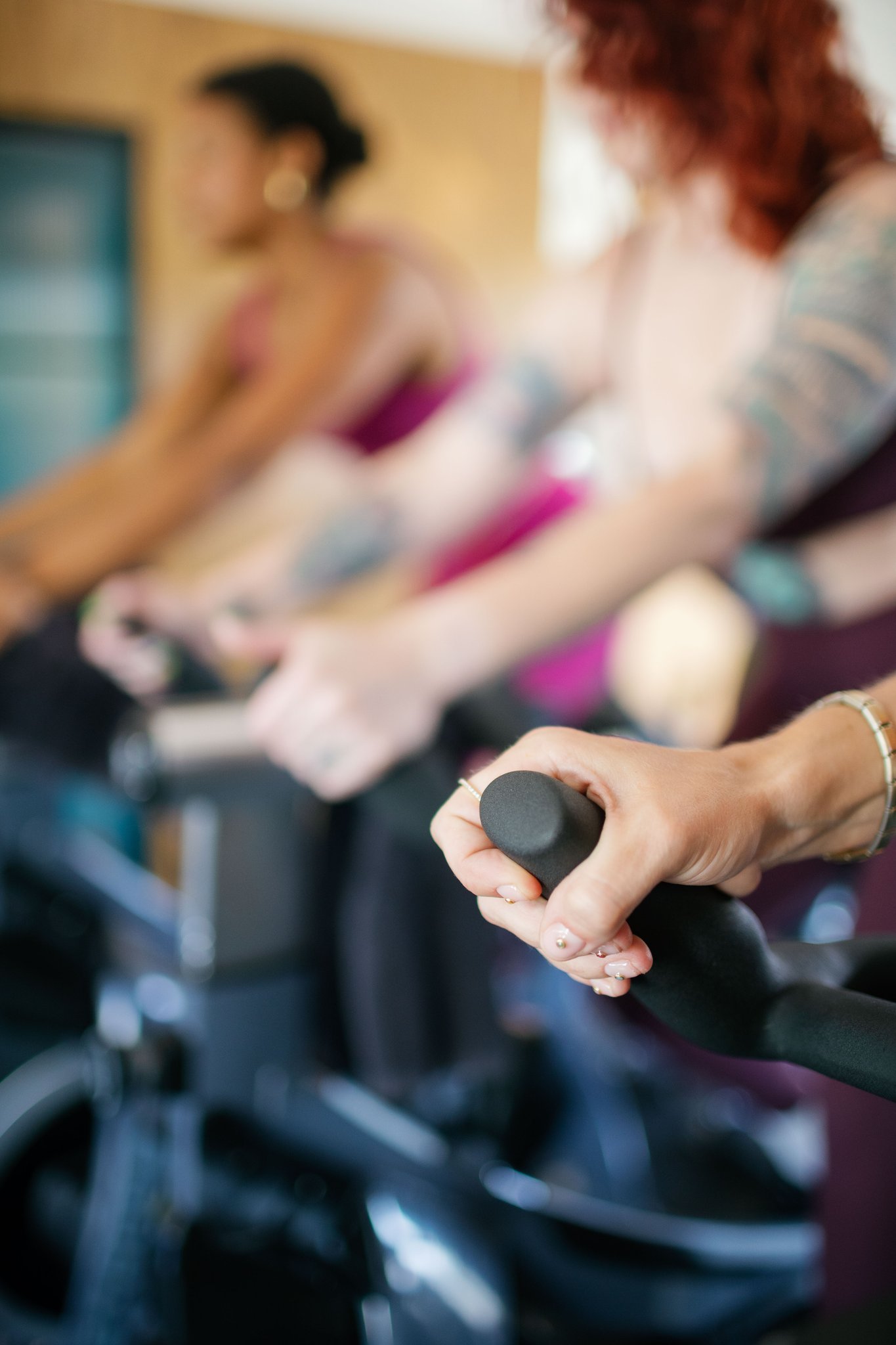 Riders gripping the handlebars during a rhythm-based cycling class at The Drop In