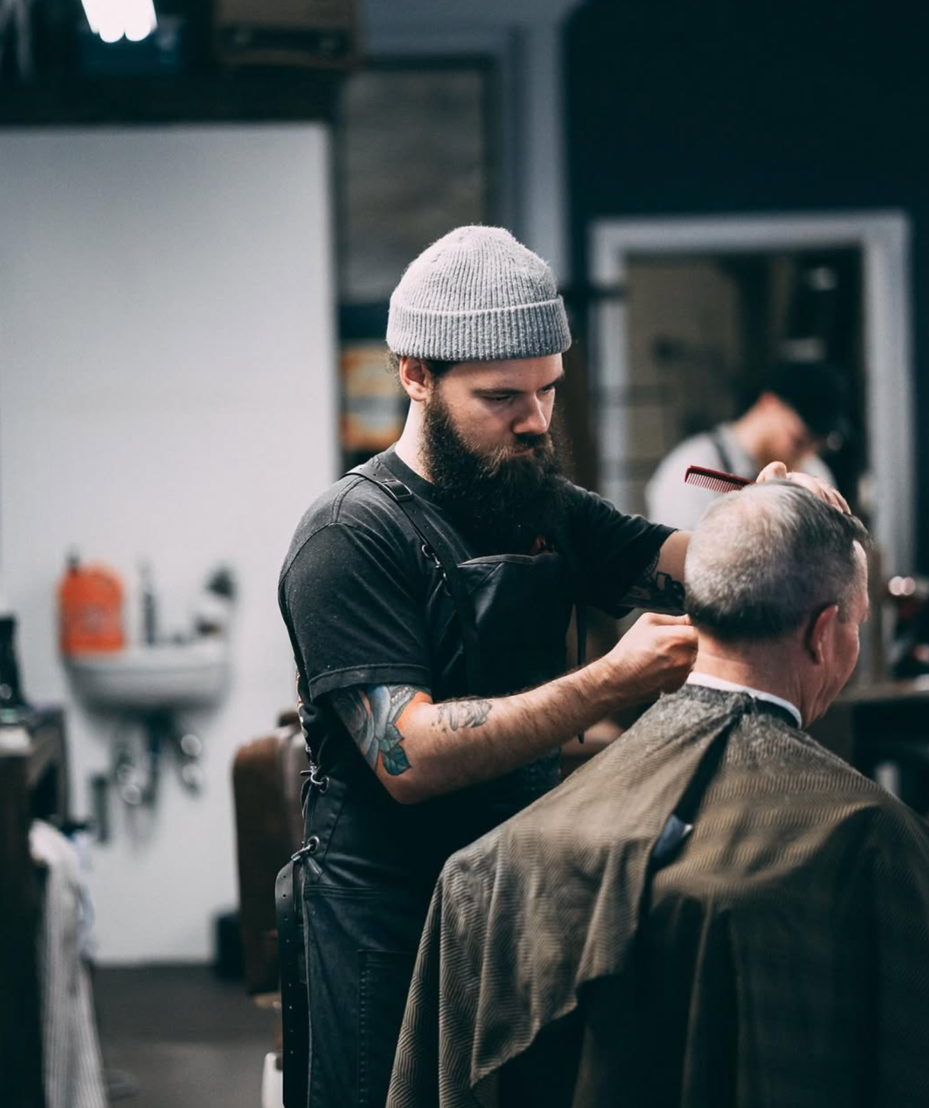 Barber giving a client a haircut at the Rebellion Barbershop at their Saanichton location, Keatinngs Cross, Rd, oVancouver Island