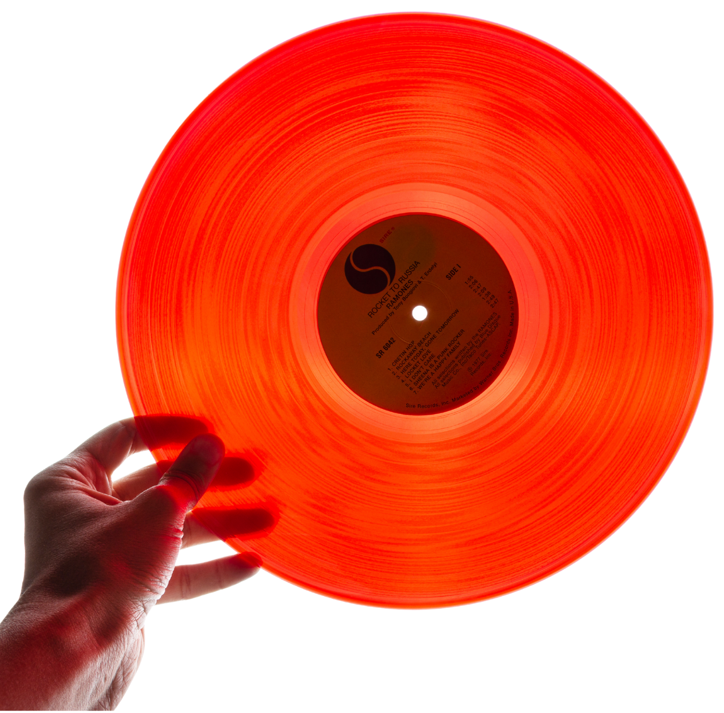 Hand holding an orange vinyl record, showcasing the music that is played at Rebellion Barbershops located in Victoria, BC.