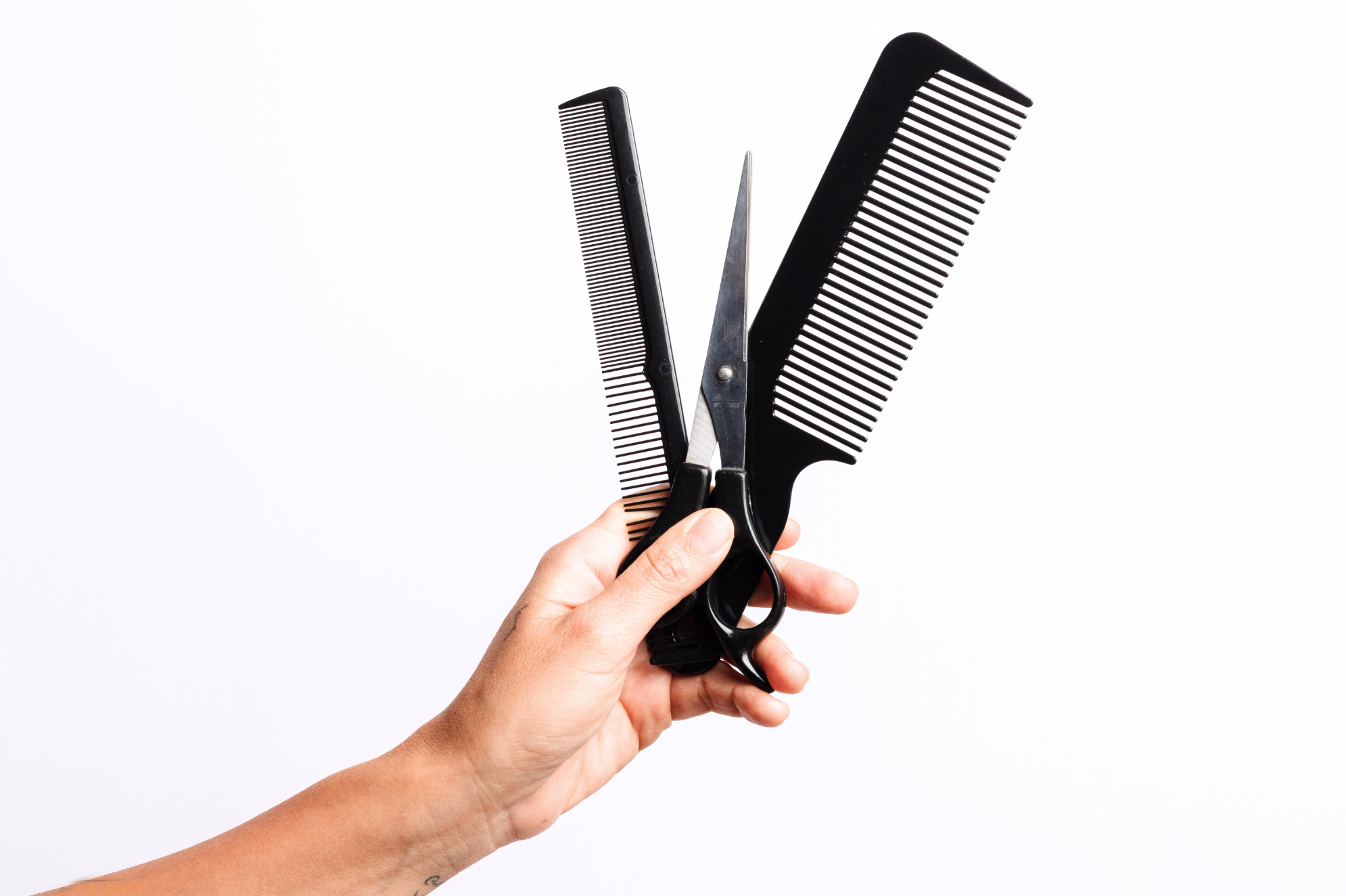 Barber holding comb and shears — Rebellion Barbershop Vancouver Island.