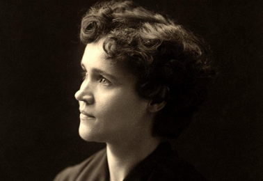 A black and white portrait of a woman with curly hair, looking to the side.