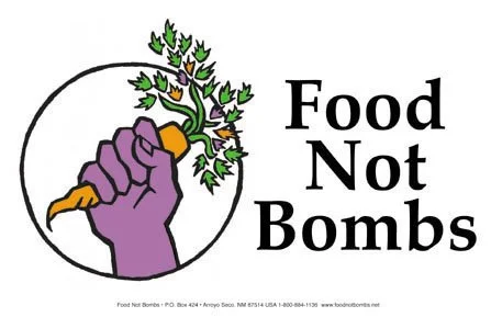 The logo of the group "Food not bombs" that shows a purple fist grasping a carrot.  The purple fist represents all races of the world, and the carrot represents the torch of liberation.