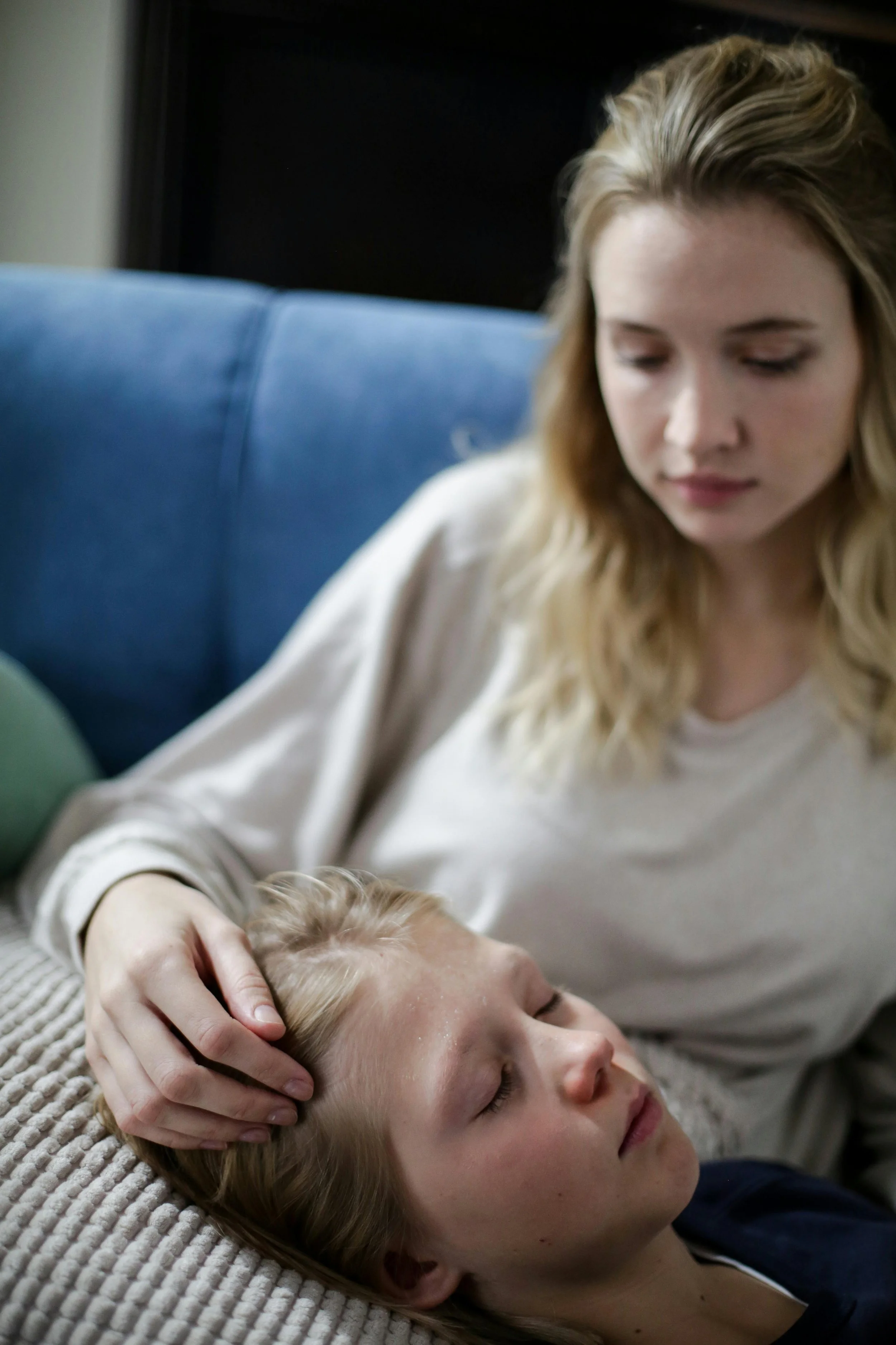 Older and younger woman relax on a couch reading together, symbolizing mental health support and connection.